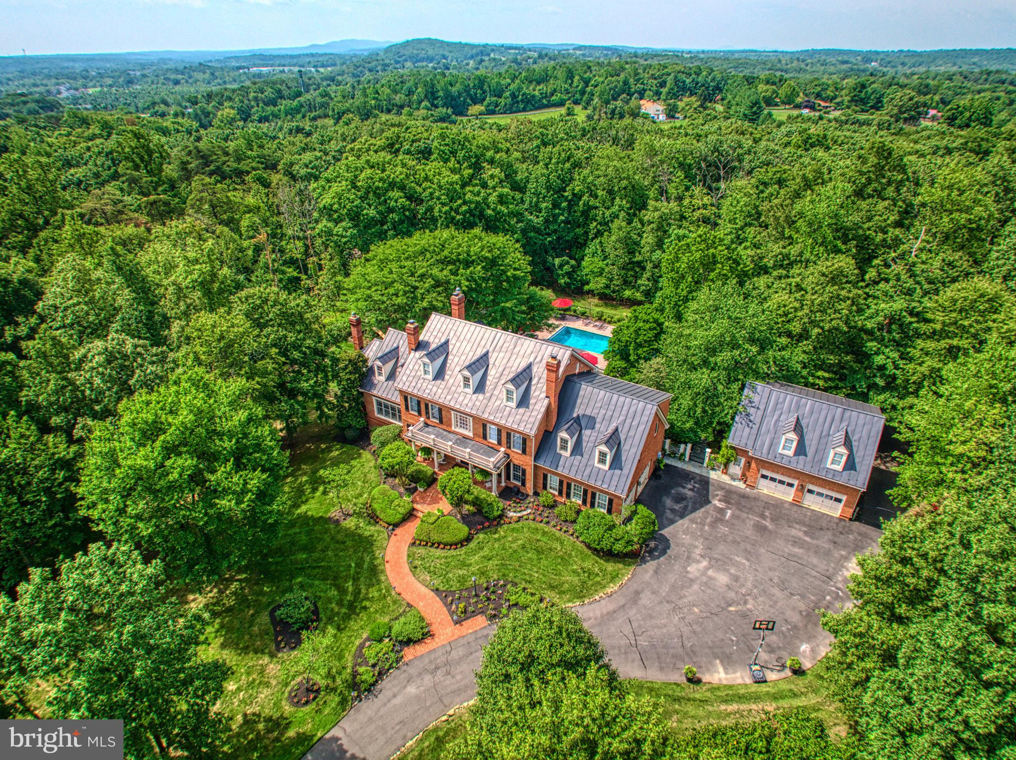 PRICED BELOW APPRAISED VALUE! Nestled within nearly 15  acres of enchanting woodlands, this Woodlea Hills estate is a sanctuary of elegance and privacy, offering a retreat-like setting on a secluded cul-de-sac. With its grand brick exterior and striking metal roof, the property combines stately appeal with over 8,390 square feet of refined living space, designed for both grand entertaining and intimate moments. The interior is a testament to craftsmanship and style, featuring exquisite designer touches, from hand-selected wallpapers and vibrant hues to intricately carved moldings and multiple stone fireplaces. Each room is a blend of comfort and luxury, with built-in showcases, elegant lighting, and custom finishes throughout. The heart of the home is a chef's dream kitchen, equipped with top-of-the-line appliances, custom cabinetry, and polished countertops, complemented by an inviting morning room for casual gatherings. The space is perfect for hosting, whether it's preparing festive meals or enjoying quiet mornings. Throughout, the home offers panoramic views of the changing seasons, with every window framing a piece of the surrounding natural beauty. Outdoors, the estate transforms with the seasons, featuring manicured gardens, serene hardscapes, and a private oasis for outdoor entertainment. Enjoy dining al fresco under a pergola, exploring serene woodland paths, or lounging by the pool surrounded by lush greenery. The property's thoughtful lighting and an outdoor kitchen make it an ideal setting for memorable gatherings. Accommodations include four luxurious bedrooms, each with its own en suite bathroom, ensuring comfort and privacy for all. The primary suite serves as a tranquil retreat, complete with a cozy fireplace and a spa-inspired bathroom. Additionally, a separate carriage house offers a one-bedroom apartment, complete with a kitchenette for guests or live-in independence. The lower level of the home extends the living space with a full kitchen, an additional bathroom, and versatile rooms for fitness, creativity, or hosting, making this Woodlea Hills residence an unparalleled haven of luxury and tranquility.