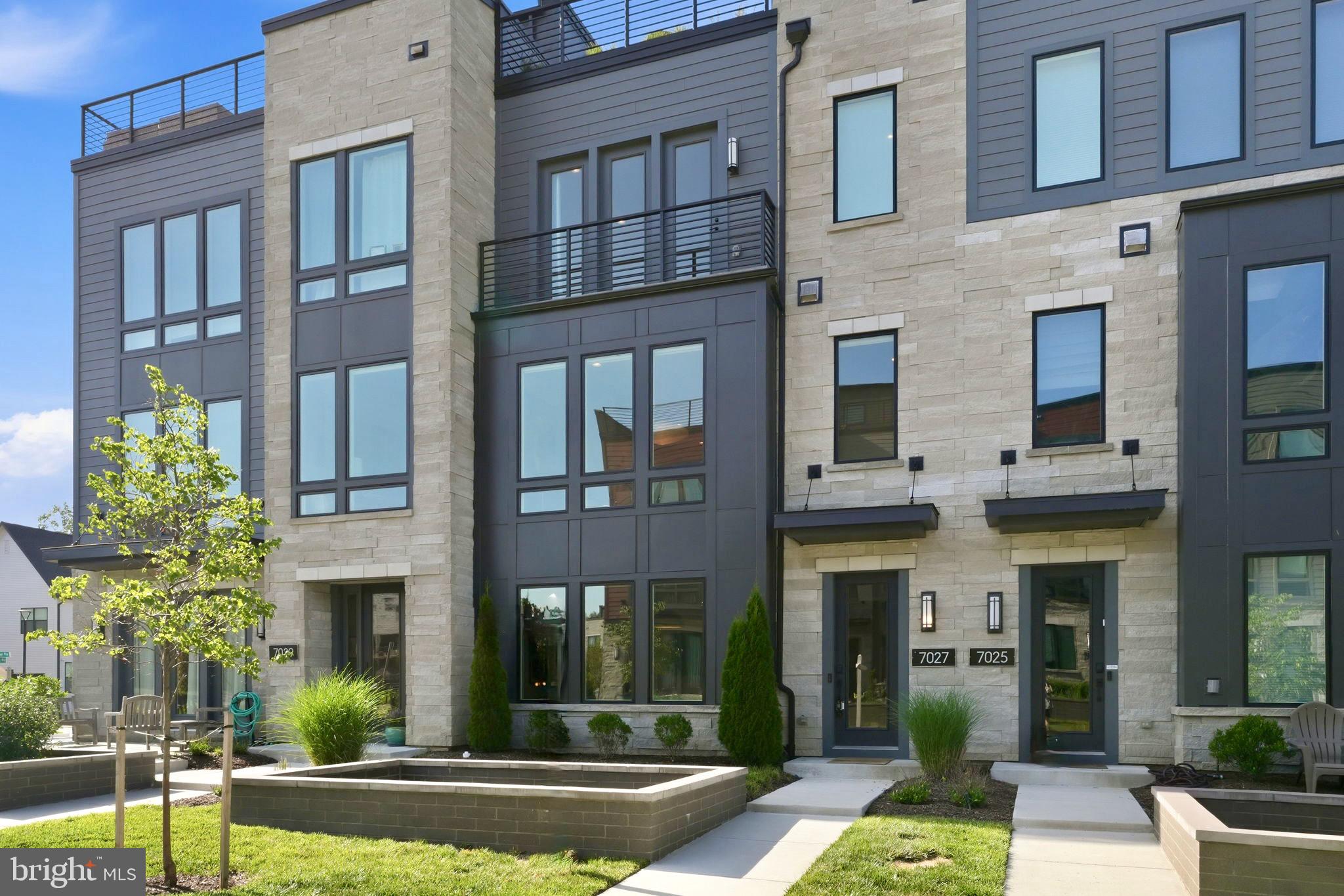 Welcome to this gorgeous Amalyn townhome, tucked into one of Bethesda's most sought-after communities. Built in 2023 and for sale by the original owners, this 3-bedroom, 3.5-bath townhome offers 2,769 square feet, a flexible fourth-bedroom-capable den, two private outdoor spaces, an attached two-car garage, and a private driveway with parking for two additional cars.

The entry level opens to a flexible living room with a full bath just steps away — ideal as a guest suite or home office and easily convertible to a fourth bedroom, suited to however you actually live.

Head up to the main level, and the light takes over — floor-to-ceiling glass walls slide open to a covered patio off the family room, blurring the line between indoors and out. The family room centers on a linear electric fireplace framed in floor-to-ceiling tile, beneath a sculptural light fixture that sets the mid-century modern tone for the whole home. The kitchen matches the moment: an expansive waterfall quartz island, full-height tiled backsplash, high end stainless appliances, gas cooking and a walk-in pantry — built for someone who actually cooks. A powder room, dedicated office space and a separate dining area with recently-added built-ins and two wine fridges round out a main level built for both daily life and entertaining.

Upstairs, the primary suite brings in the same oversized glass, a generous walk-in closet, and an en-suite bath with a double vanity and frameless glass shower. Two additional bedrooms share a well-appointed hall bath, and a dedicated laundry room completes the level.

At the top of the home, a private rooftop terrace — over 700 square feet — is anchored by a natural gas fire pit and built-in gas grill, perfect for entertaining above the rooftops of Bethesda.

Beyond the front door, the Amalyn lives like a resort. Residents have access to a 4,000-square-foot clubhouse with indoor and outdoor fitness space, a resort-style pool with cabanas, a Zen garden, and walking trails connecting to Station Park. It's the kind of amenity package you'd expect to pay club dues for elsewhere — here, it's part of daily life.

The location delivers too: Westfield Montgomery Mall, Giant, Balducci's and several restaurants are all within about a mile and a half. The Amalyn Community is now fully built out, and this is one of only a couple of resale homes currently on the market — still like new, with thoughtful additions taking it to the next level.