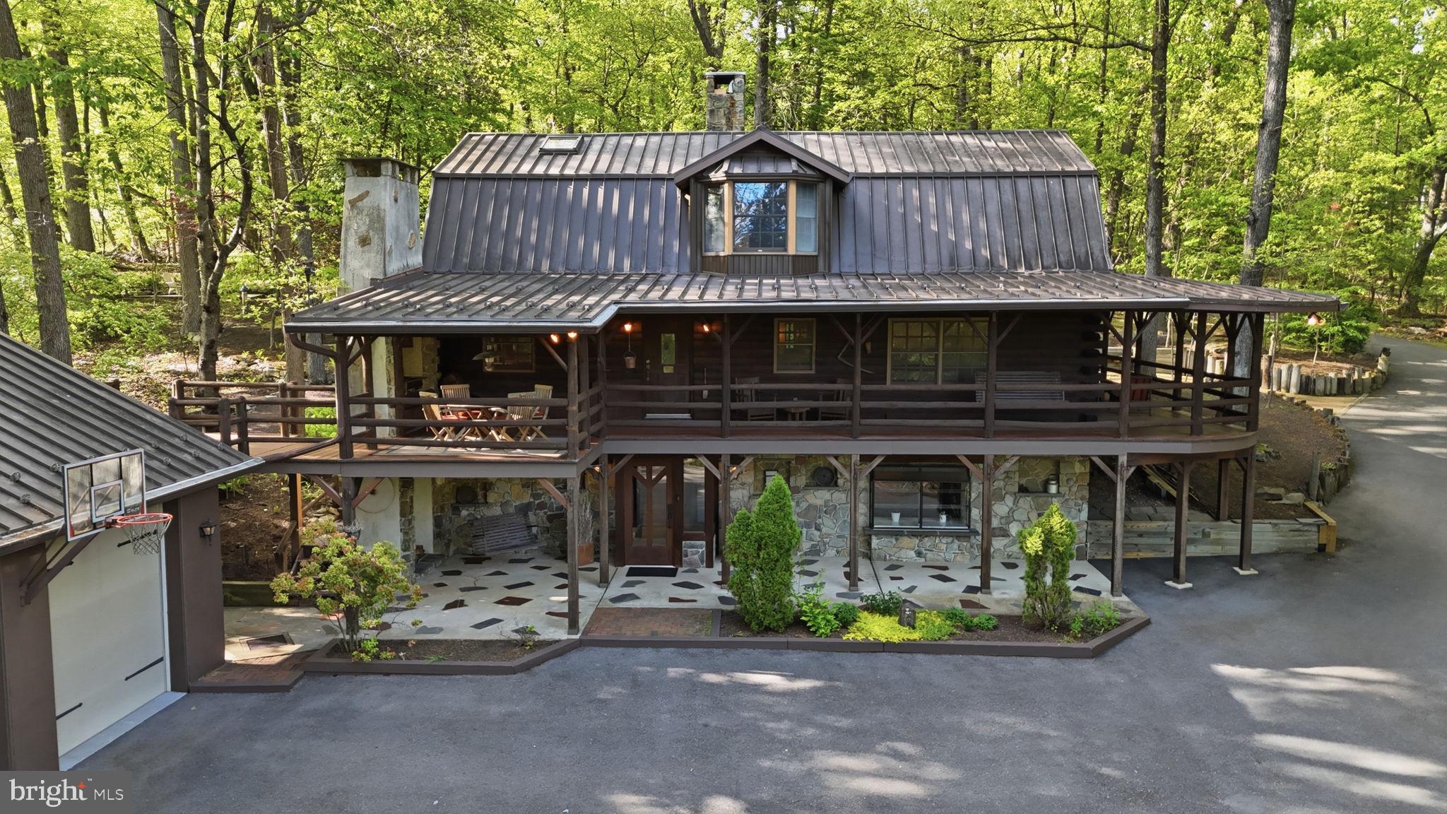 Tucked behind a canopy of tall trees on more than 4.5 private acres along a quiet country road in sought-after Lower Saucon Township, this one-of-a-kind log retreat on Springtown Hill Road delivers the soul of a mountain escape without sacrificing a single convenience: a brick walkway winds past a serene koi pond spanned by a wooden footbridge, the stained glass front door opens to beamed ceilings, authentic log walls, and exposed stone accents, and a dramatic double-sided stone fireplace anchors both the living and dining rooms, while a custom removable banquette, bright kitchen with brushed aluminum cabinetry and walk-in pantry, private office, and half bath round out the thoughtfully designed main level, with three spacious bedrooms and a full bath upstairs, and a fully finished walkout lower level complete with wet bar, wood-burning fireplace, and full bath below; step outside onto the enormous covered wraparound deck with an outdoor kitchen to watch deer and songbirds move through the meticulously cultivated shade gardens, then explore everything the community offers, from the Saucon Rail Trail and Lost River Caverns to Black River Farm's vineyard weekends, Hellertown's thriving dining scene, and quick access to Route 78, Bethlehem, the Promenade Shops at Saucon Valley, and the charming boutiques of Doylestown to the south. Saucon Valley School District.