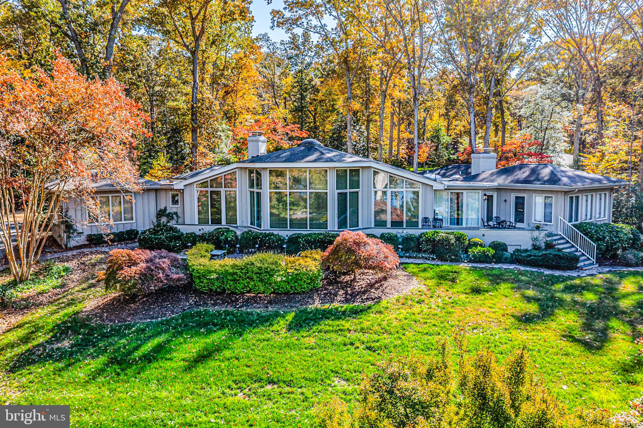 Treetops is an exceptional waterfront estate on the Corrotoman River, masterfully designed by architect Milton L. Grigg in the spirit of “Jeffersonian modernism.” The home’s graceful symmetry, soaring ceilings, and walls of glass create a seamless connection to the river and surrounding natural beauty. A tree-lined approach leads to the private 6-acre property, where manicured lawns, mature landscaping, and panoramic water and sunset views define a serene retreat. Inside, elegant gathering spaces include a formal living room with a fireplace, a dining room overlooking the river, and a light-filled morning room that opens to the kitchen and casual family room. The primary suite offers sweeping river and sunset vistas, dual closets, and a luxurious marble bath. A separate guest suite with two walk-in closets and a private bath, plus two additional bedrooms and a shared hall bath, ensures comfort for family and guests. The grounds feature a riverside pool terrace perfectly positioned to enjoy dramatic evening skies, a guest house with a living area, kitchenette, and bedroom, and a dock with a boat lift—ideal for boating, fishing, and sunset cruises. The pair of matching two-bay garages echoes the home’s architectural rhythm. A two-acre building site is also included, creating added value and potential for expansion or additional accommodations. Blending classic design with timeless craftsmanship, Treetops offers tranquility, privacy, and breathtaking sunset views in one of Virginia’s most sought-after waterfront settings. Conveniently located near Irvington, Kilmarnock, and White Stone, this rare property captures the essence of refined riverfront living on the Northern Neck.