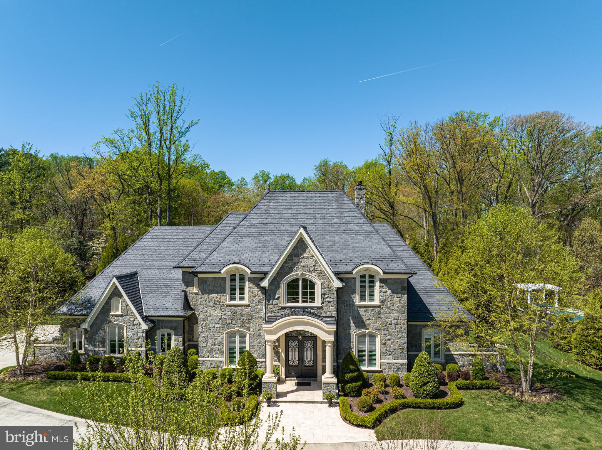 Prominently sited on nearly an acre in the prestigious Mackall Farms neighborhood of McLean, 953 Mackall Farms Lane is an extraordinary 2014 built French-style custom residence embodying the pinnacle of luxurious, grand scale living. Encompassed by pristine landscaping and lush gardens, the expansive property boasts an enviable pairing of magnificently curated interiors and sensationally crafted outdoor living spaces, creating the ultimate oasis just minutes from our nation’s capital. Breathtaking millwork, high-end fixtures and the finest of finishes span throughout the 8,300 SF home’s expansive open floor plan. Complementing the interior’s luxurious layout, an extensive walk-out stone Patio surrounds the home’s 30’ heated Pool and outdoor Pavilion, offering idyllic al fresco dining and entertaining by the outdoor BBQ Grill or limestone Fire Pit. Providing premiere main-level living with 10’ ceilings, the 4 BR, 4 BA, 2 HB stately residence boasts a grand welcome with a two-story marble Foyer flanked by an elegant Dining Room and private Study. The Gourmet Kitchen is fit for any caliber chef with rich mahogany cabinetry, Wolf and Subzero luxury appliances, two Islands and a Breakfast Area for more informal dining. Open from the Kitchen, the Great Room features a stunning built-in entertainment system, beautifully coffered ceiling, stone fireplace surround and French doors leading to the walk-out rear stone Patio for seamless entertaining. The Main Level features a sprawling Billiards Room complete with an expansive Bar, a Home Theatre soundproof acoustic paneling and an Exercise Room overlooking the gardens. A generous, Main Level, Primary Suite with Pool views provides walk-out access to the rear Patio and features outfitted walk-in closets and a spa-like Primary Bathroom complete with dual vanities, soaking tub, heated floors, and walk-in shower. The guest quarters are located on the Upper Level and include a second Primary Suite as well as two additional en-suite Bedrooms and ample storage space. Additional storage space is also available on the Lower Level with a crawl space spanning the length of the home. An oversized 3-Car Garage with EV Charging and multiple Driveway Parking Spaces complete the abundant amenities this Mackall Farms oasis has to offer.