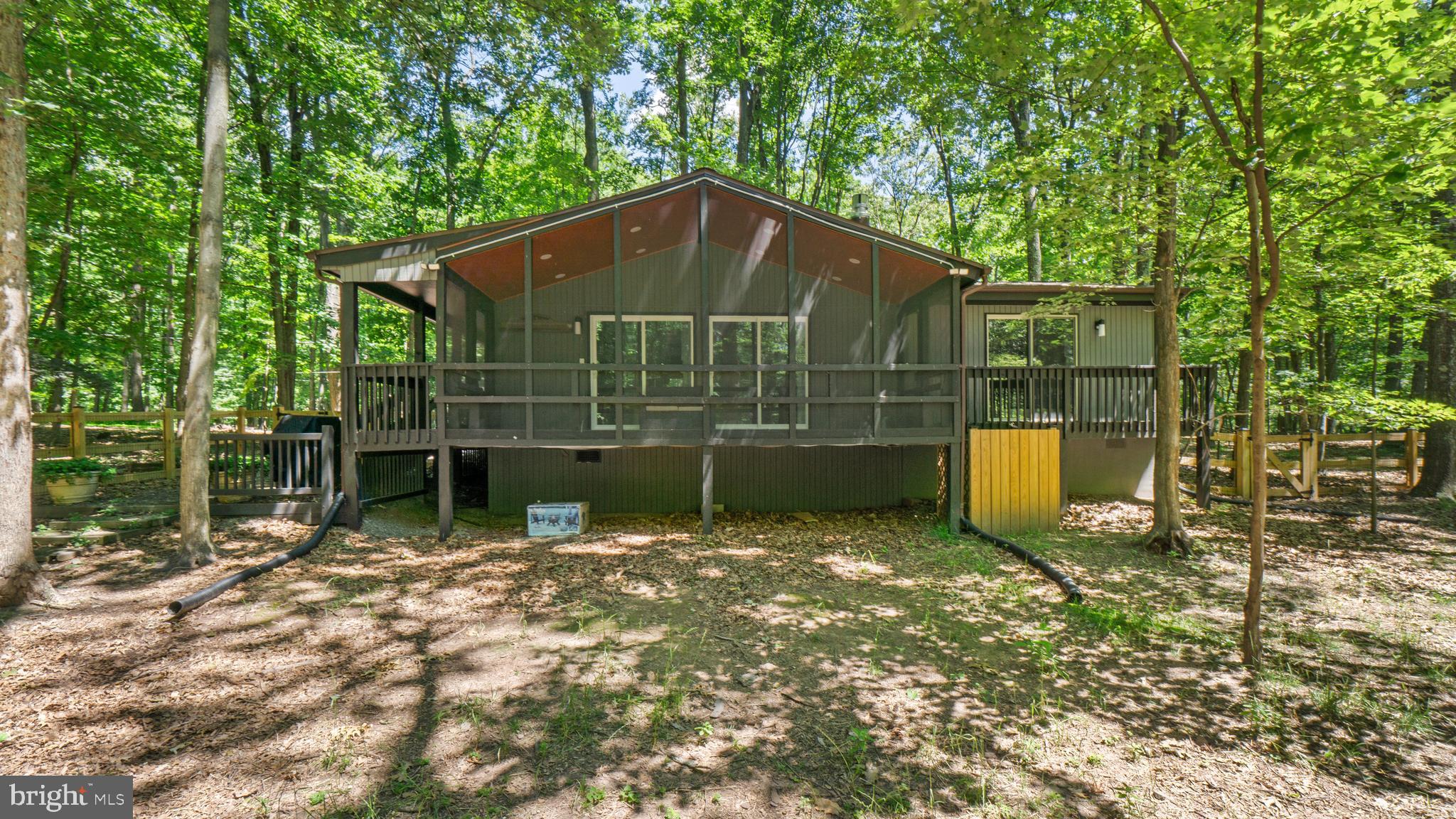 Cozy Cabin in The Woods Resort. Tucked away on a private wooded lot in desirable The Woods Resort, this inviting 3-bedroom cabin blends rustic charm with thoughtful modern updates. The spacious primary suite features a private deck, ideal for morning coffee or unwinding in the evening.
Inside, the updated kitchen and living area are warmed by a new gas fireplace and feature luxury vinyl plank flooring, granite countertops, stainless steel appliances, upgraded lighting, and brand-new carpet in the bedrooms. Additional recent improvements include new windows, blinds, storm door, hot water heater, heat pump, electrical upgrades, and a new half bath in the primary bedroom.
Outdoor spaces are designed for relaxation and entertaining, with a large screened-in porch, an expansive front porch, a generous driveway, and an outbuilding for added storage. Several pieces of furniture convey, adding even more convenience. With its many upgrades and peaceful setting, this property would make an excellent primary residence, vacation home, or investment property, all just moments from the amenities of The Woods Resort. Membership fees and additional information are available by contacting The Woods property manager, Dawn Lewis.