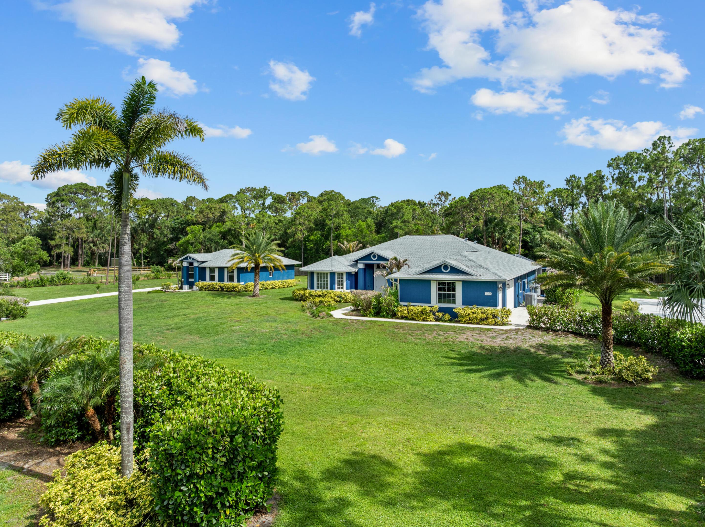 Set on 2.5 fully fenced acres in a desirable paved-road location, this Jupiter Farms property offers the space, flexibility, and privacy buyers are constantly searching for, complete with two separate homes, a heated saltwater pool, extensive parking, and room to grow.  Built in 2020, the main residence features 4 bedrooms, 3 bathrooms, a dedicated office/den, and approximately 2,300 square feet of thoughtfully designed living space that feels fresh, current, and completely move-in ready.  The outdoor space was designed to be enjoyed year-round, featuring an oversized screened and heated saltwater pool with a large sun shelf, volleyball setup, swim tethers, and an expansive pool deck with plenty of room to gather, entertain, or simply enjoy the privacy of your own backyard. A 3-car garage, mature coconut and Sylvester palms, and extensive parking for multiple boats, RVs, trailers, and vehicles add to the property's appeal.  The detached guest house offers approximately 912 square feet with 2 bedrooms, 1 bathroom, a full kitchen, living area, private entrance, and its own concrete driveway. Whether used for extended family, guests, a home business, multigenerational living, or rental income potential, it creates opportunities that few properties can offer.  The entire property is fenced, including a 6-foot privacy fence along the rear boundary, with ample room for a large workshop, toy barn, stables, additional garages, or future expansion.  Properties offering two newer homes, a heated pool, extensive parking, and 2.5 usable acres are rarely available. Conveniently located in Jupiter Farms, this property offers the freedom, functionality, and flexibility that make acreage living so appealing.
