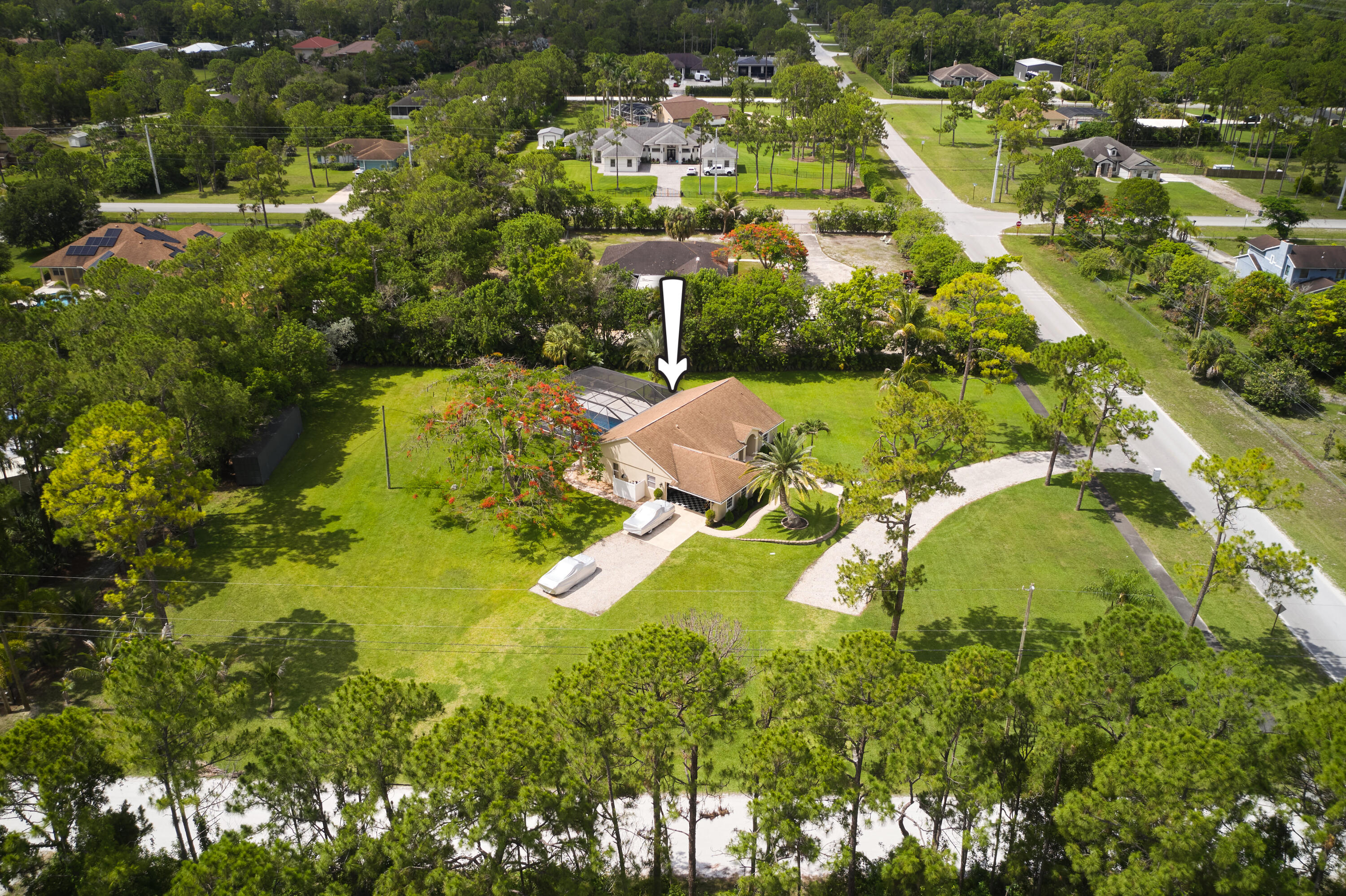 Private acreage, a resort-style screened pool, a paved-road corner lot, and no HOA make this updated CBS home a standout in Loxahatchee. Set on 1.66 acres, this 3-bedroom, 2-bath residence offers the space, privacy, and flexibility buyers want, with many major improvements already completed.  The outdoor living area is the true showstopper. Fully remodeled in 2022, the automated heated pool features a raised wall with a water feature, LED deck jets, and color-changing lighting. The screened patio was also redone in 2022, creating a comfortable, private setting for entertaining, relaxing, and enjoying the Florida lifestyle year-round.  Inside, the bright, open kitchen features granite countertops, stainless steel appliances, soft-close cabinetry, LED lighting, and smart switches.  The updated bathroom showcases quartz countertops, a custom vanity, glass mosaic accent wall, custom glass shower enclosure, rain showerhead, and high-speed body jets.  Additional improvements include a new A/C system in 2022, tankless water heater in 2020, water pump and filtration system in 2021, smart sprinkler system, remodeled garage in 2023, new washer and dryer, updated security system, and recently completed interior and exterior paint.  With 1.66 acres, a screened heated pool, paved-road access, a desirable corner lot, and no HOA restrictions, this property offers an exceptional combination of privacy, upgrades, and outdoor living.