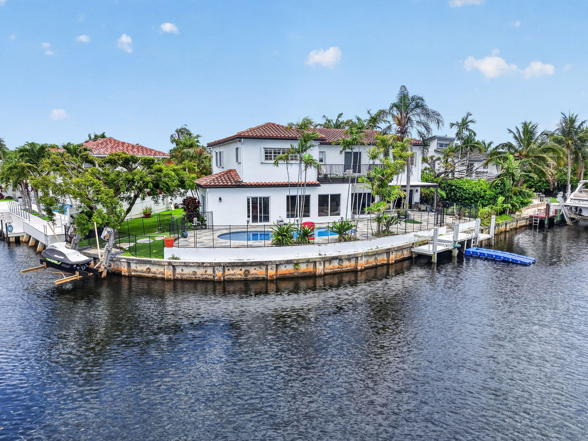 Rare opportunity to own a premier East Boca waterfront residence featuring 147 feet of ocean-access waterfrontage, a private dock, and a 5,000-pound boat lift. Offering 4,518 square feet of living space under air, this expansive home combines exceptional waterfront living with a highly functional floor plan ideal for both everyday living and entertaining. The residence features 7 bedrooms, 4.5 bathrooms, and a two-car garage. An updated kitchen serves as the centerpiece of the home, while impact glass throughout frames beautiful views of the pool and wide waterway, filling the interiors with natural light.   The versatile layout includes two first-floor bedrooms, one currently configured as a home office, and five additional bedrooms upstairs. Designed to embrace the South Florida lifestyle, the home features a dedicated pool room overlooking the outdoor living area, sparkling pool, and tranquil waterfront setting. With extensive waterfrontage, ocean access, private dockage, and ample space for family and guests, this property presents an exceptional opportunity in one of East Boca Raton's most desirable waterfront locations.  Ideally situated just minutes from Boca's pristine beaches, world-class dining, shopping, and entertainment, this waterfront retreat offers the perfect blend of boating lifestyle, comfort, and location.