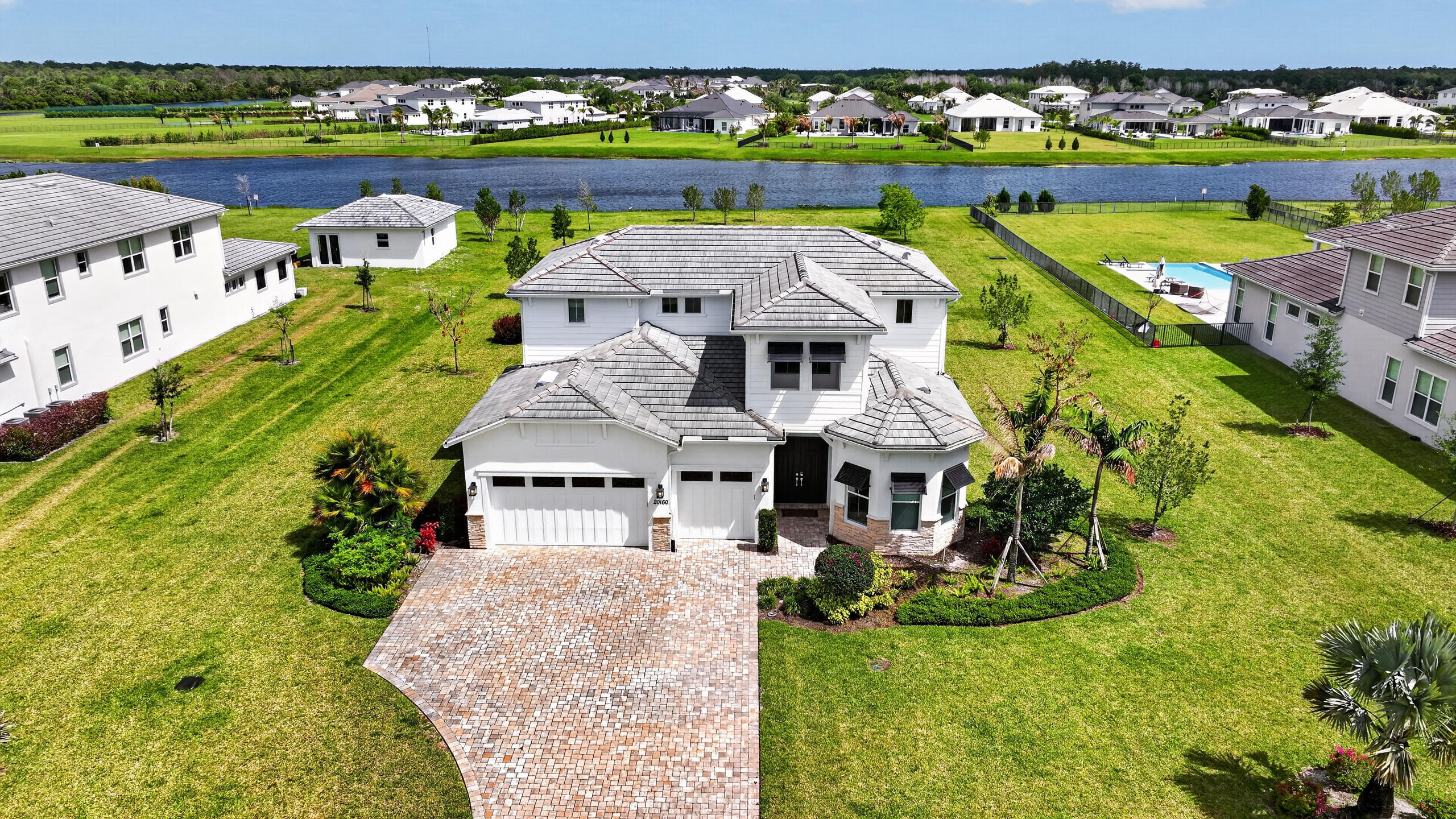 A private lakefront estate situated on 1 acre in Bridgewater, Jupiter's newest premiere gated community! This 2023-built residence spans 4,020 square feet of beautifully designed living space. Three large bedrooms and a den span the first floor, and upstairs features a fourth bedroom, full bathroom, and expansive loft (easily converted to a fifth bedroom). The main-level owner's suite features a bay window overlooking the lake and grounds, and a relaxing bathroom retreat. Highlights include a gourmet kitchen with breakfast nook, wood floors and porcelain throughout, complete impact glass, three-car garage, and an expanded covered lanai. The homesite offers ample room for a custom pool and more: build a guest house/in-law suite and private tennis court if you wish! Enjoy estate living with  the space, privacy, and proximity that make Bridgewater one of Jupiter's most sought-after communities.
