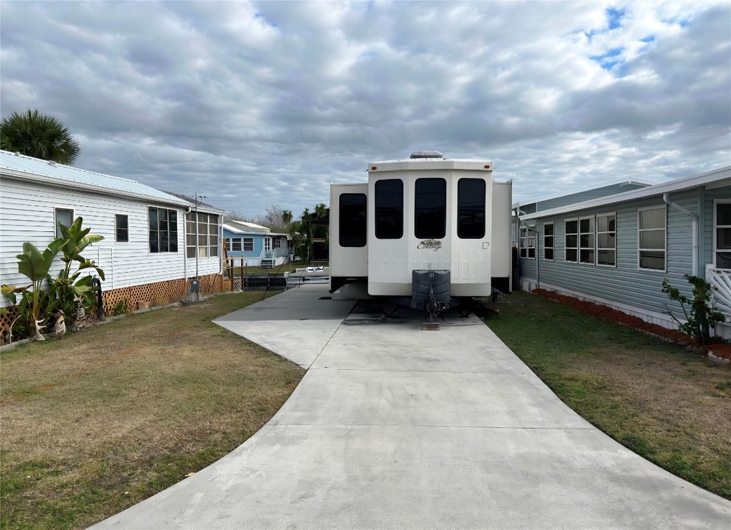 Enjoy waterfront living in Turtle Cove with this well-maintained 2015 Cedar Creek Cottage park model camper offering approximately 30’ of waterfront in a desirable 55+ community. The interior features a full kitchen with island seating, spacious living area, dining space, private bedroom, and stackable washer and dryer. Multiple slide-outs create an open, comfortable layout filled with natural light. Exterior highlights include a concrete pad and covered entry ideal for relaxing by the canal. An additional lot across the road conveys with the purchase, featuring a small storage shed for added flexibility. Ideal for seasonal or low-maintenance Florida living. Camper/RV classification. Buyer to verify park rules.