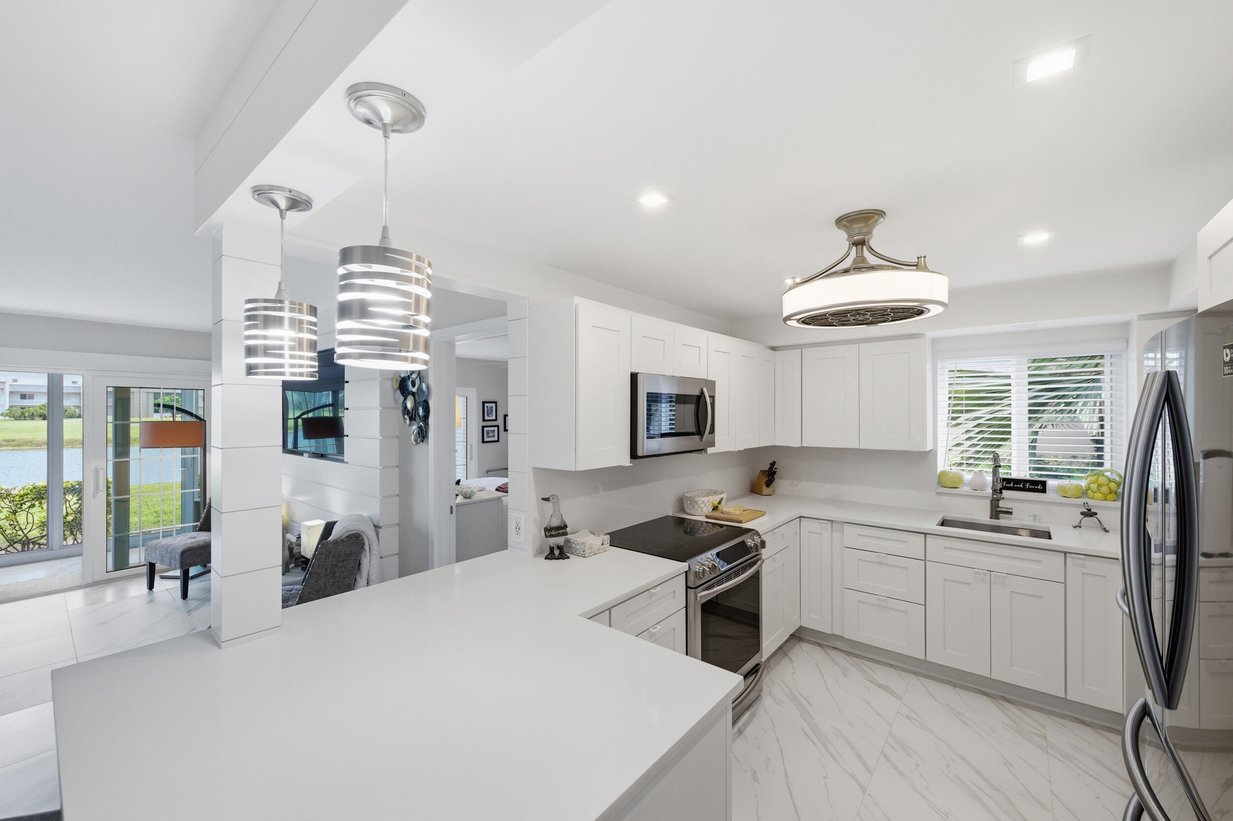 Rarely does a home so clearly reflect the creativity and vision of its owner. This exceptional ground-floor waterfront residence was thoughtfully redesigned by the owner to maximize space, natural light, storage, and functionality while creating a sophisticated yet welcoming atmosphere. Every detail was personally selected, from the custom finishes and designer lighting to the stunning floating vanities, spa-inspired bathrooms, elegant kitchen, and custom closet systems, resulting in a home that feels both luxurious and effortlessly livable. The stunning open-concept kitchen serves as the centerpiece of the home, featuring abundant cabinetry, premium finishes, designer lighting, and a layout that seamlessly connects the living and dining areas. Large tile flooring throughout  enhances the bright, expansive feel, while the intelligent design allows the home to live far larger than its footprint. Natural light pours through all impact windows and impact sliding glass doors, showcasing breathtaking water and golf course views from nearly every room. The enclosed patio becomes a true extension of the living space, creating the perfect setting to relax, entertain, or simply enjoy the tranquil waterfront scenery. Both bathrooms have been beautifully redesigned with floating vanities, frameless glass showers, contemporary finishes, and a clean spa-inspired aesthetic that enhances the home's open and airy feel. The spacious primary suite offers comfort, style, and exceptional storage through thoughtfully designed custom closet systems. Additional upgrades include a newer AC system, brand-new roof, impact-rated windows and doors, designer fixtures, custom lighting, and numerous thoughtful improvements throughout. Located in the highly desirable Kings Point active adult community, residents enjoy access to resort-style amenities including multiple clubhouses, indoor and outdoor pools, fitness centers, golf, tennis, pickleball, entertainment, dining, social clubs, courtesy transportation, and countless activities. Conveniently situated just minutes from the vibrant shops, restaurants, galleries, and nightlife of Atlantic Avenue in Downtown Delray Beach, as well as nearby shopping centers, medical facilities, major highways, and South Florida's beautiful beaches. Combining exceptional design, intelligent space planning, spectacular water and golf course views, premium upgrades, and an unbeatable location, 53 Piedmont B is one of the most distinctive and move-in-ready residences available in Kings Point today.