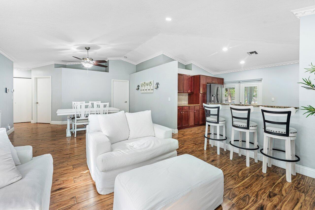 Experience your own piece of Florida tropical living, surrounded by lush landscaping including mango trees, red ginger, palms, canna lilies, and clusia in a generously sized backyard. This bright and spacious 3-bedroom, 2-bath home showcases soaring vaulted ceilings, elegant crown molding, recessed lighting, and a beautifully open floor plan designed for comfortable living and easy entertaining. The kitchen features rich chestnut-brown cabinetry, granite countertops, and stainless-steel appliances, creating a stylish and functional space for everyday meals or hosting guests. The spacious primary suite offers a walk-in closet and a desirable split-bedroom layout that provides added privacy from the additional bedrooms. Step outside to enjoy tranquil outdoor living on the screened-in patio overlooking lush green space with no rear neighbors. Located in a quiet, hidden-gem neighborhood in the Town of Haverhill, the home is just minutes from Downtown West Palm Beach and Wellington. A peaceful park with a walking trail is only steps away. Low HOA fees include landscaping, making it easy to enjoy the beauty of the community without the upkeep.