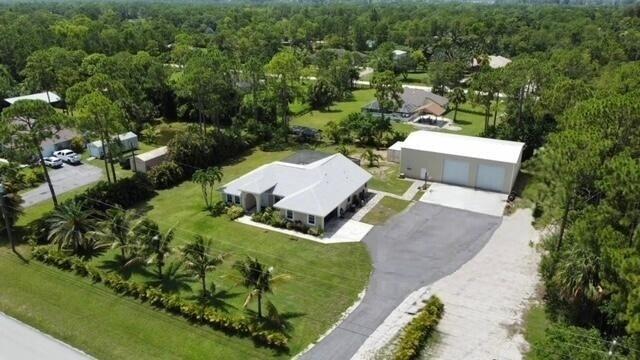 Unique well-maintained move-in ready 3/2/2/ CBS home with pool & huge 2400sf detached garage/shop on paved road in The Acreage.  Open concept split floor plan.  Security system, paved driveway, nicely landscaped with mature trees and areca palms bordering property providing privacy.  Re-roof 2020, new a/c, water softener system & pool salt system 2021, remodeled kitchen Oct 2025, brand new washer & dryer.  The 2400sf garage/shop includes 20x10ft bonus room with a/c, 14'x14' roll up doors, 6" reinforced concrete floors.  Prefect to bring your toys (boats, RV's, etc) or work shop/business.