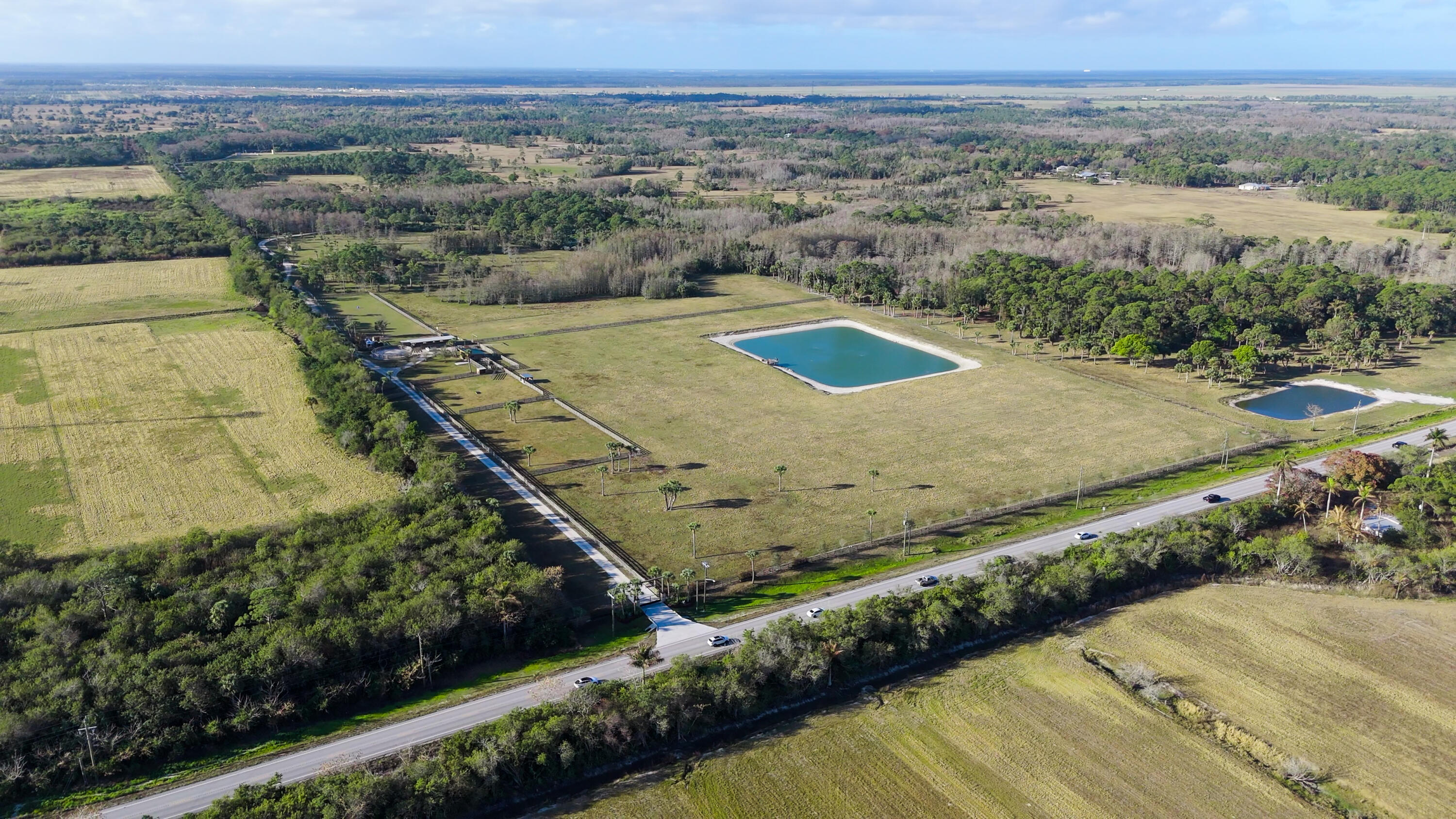 A rare 100-acre private compound in Hobe Sound offering exceptional privacy, control, and scale just 5 minutes from Jupiter Island and the Atlantic Ocean.  Positioned along SE Bridge Road, the property features a 1.25-mile private gated drive creating a secure, low-visibility arrival experience. The estate backs to approximately 3,600 acres of privately held land, delivering an uncommon level of buffer, quiet, and long-term privacy in coastal South Florida.  Designed as a fully self-contained environment, the property allows for complete control over access, circulation, and use across distinct operational zones. The land has been professionally laser-leveled with engineered drainage infrastructure, supporting long-term stability and high usability across the entire site. Infrastructure is positioned to support multiple lifestyle and operational uses simultaneously without overlap or disruption. Recreational systems include a 400-yard long-range shooting facility, separate short-range range, sporting clays course, Olympic-grade trap field, and on-site fitness and training facility.  The equestrian and lifestyle zone is intentionally separated and includes six fenced paddocks, an impact-resistant double-stall barn, three additional open-air stalls, a tack room, and a round pen with drainage tied to a sub-pump system. This area functions as a flexible lifestyle component rather than the core identity of the estate.  Additional features include two stocked freshwater ponds, a private internal trail system, and an extensive internal road network enabling seamless movement throughout the property.  With AG zoning in place, the property offers exceptional flexibility as a private estate, executive retreat, recreational compound, equestrian property, or long-term land holding.  Located within one of South Florida's most active migration corridors for high-net-worth and ultra-high-net-worth buyers relocating from Miami and out of state, the property combines immediate access to coastal amenities with complete spatial separation from surrounding development.  Proximity to Jupiter Island, Palm Beach County, US-1, and I-95 provides connectivity while preserving full privacy and control—an increasingly rare combination in coastal Florida.