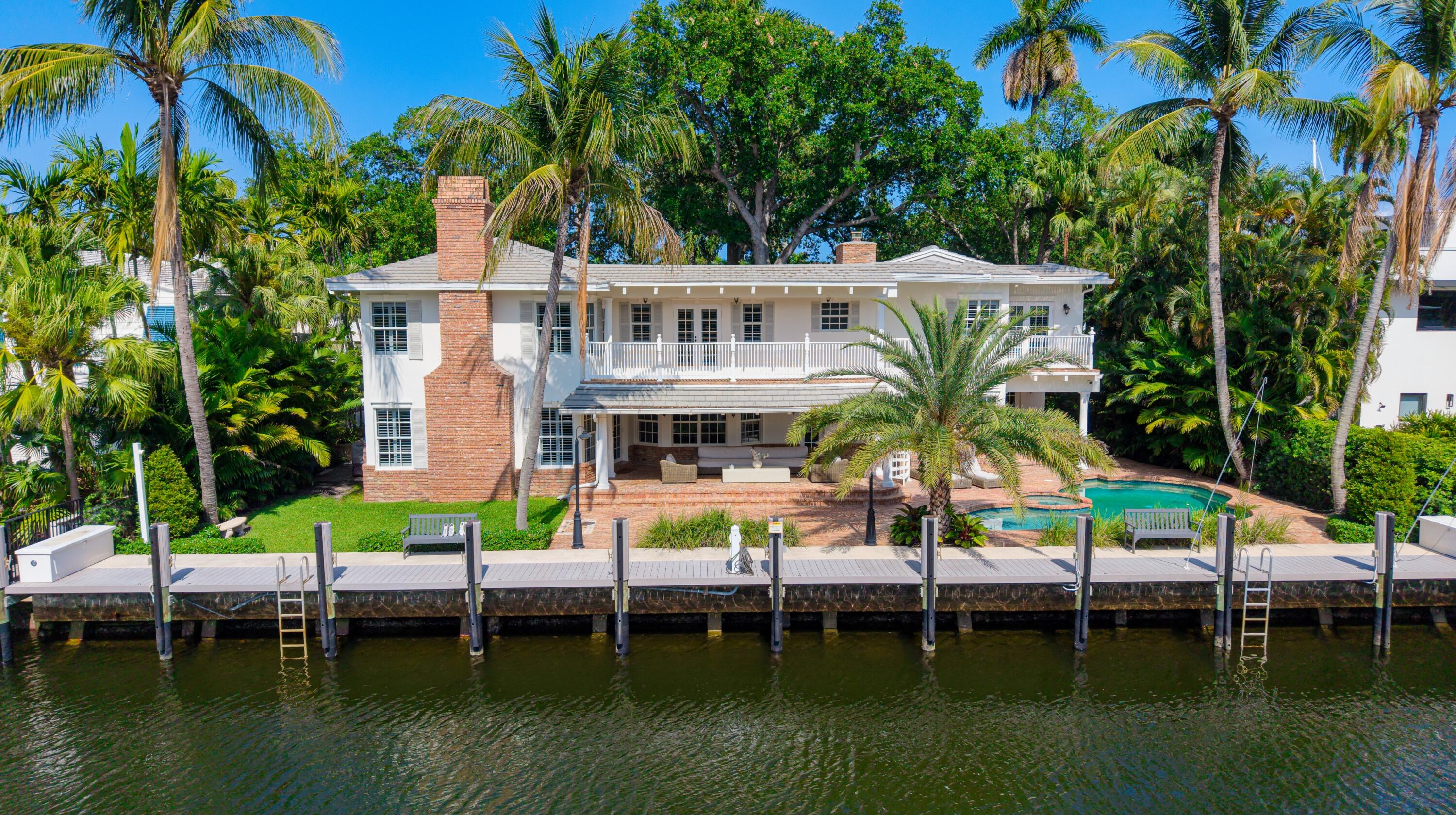 Charming Coastal Colonial Deepwater Estate sited on 100' of water-frontage offering stunning views, a few homes from the point on Coral Way. A sought-after address on the southern side of Las Olas Isles, nestled under a canopy of trees with a sprawling green-carpeted lawn, this 5,004 sq. ft. residence offers 6 bedrooms, each with its own balcony, plus a dedicated office/den, with 4 full & 1 half bathrooms. Details include an easy-flow layout perfect for entertaining, sanded white-oak flooring, touches of Chicago brick, custom cabinetry, handsome moldings and plantation-shutters shading impact-glass windows and doors. Newer improvements include a concrete seawall & composite dock with 100-amp service (2022), tile roof (2018), and a recent upgrade along the street with underground utilities.