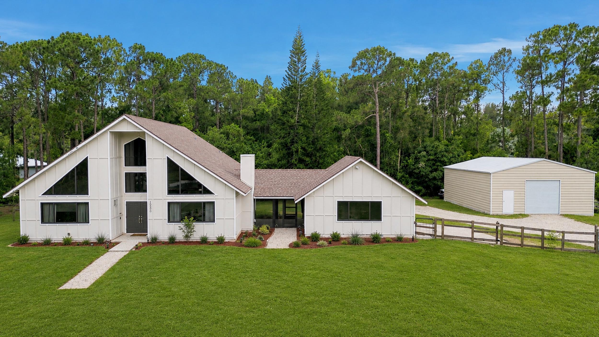 WELCOME HOME This well-appointed rare A-frame doll house home is resting on a premium 1.14 acre lot and boasting 3 bedrooms, 2 baths, 2 car attached garage that would be a perfect studio apartment or quest home for multi-generational living, PLUS a 2024 30'x40' 1200sqft shop, upgrades and updating galore, 2024 hurricane impact windows and doors, 2026 BRAND NEW roof coming soon (see photos), offering the perfect blend of luxury, function and this beauty is in a superb location! ENTERING you will discover that this gem is resting on a high and dry lot with no pond. Then you will be greeted by the charming front patio and the double front doors will bring you inside where you are greeted by soaring 21' ceilings, high-end flat wall finish, beautiful millwork and solid core doors, (CLICK) windows galore and loads of natural lighting, spectacular kitchen that features stainless steel appliance package, 42 inch soft close cabinets and draws with luxury stainless steel hardware, quartz countertops, 4'x7' waterfall kitchen island with abundant storage and kitchen desk, built-in wine cooler, floating shelves, large walk-in pantry with a barn door, stainless steel deep sink with a lovely window that overlooks the abundant green space. PASSING THROUGH you will find a modern farm house feel, elegant triangle windows, dynamite floor plan, tile plank porcelain flooring in a herringbone pattern throughout first floor, luxury/waterproof extra thick vinyl flooring throughout second floor, two downstairs bedrooms and the primary suite upstairs, grand vaulted ceiling throughout, lovely color palette, green space views and a spacious primary suite boasting a walk-in closet with built-ins, deluxe soaking tub, large walk-in shower, linen closets and a design that is exquisite! STEPPING OUTSIDE brings you into a your very own private retreat... 14' x 12' screened in lanai, mature pine trees, cabbage palms, orchid tree, pygmy date palm, two convenient driveways and so much more. Simply, a perfect space for quiet time, cozy fires, family gatherings, entertaining, building a pool and enjoying Florida living at its best. HELLO SHOP, EXTRAS, SAVINGS, PEACE OF MIND & CONVENIENCE Eversafe shop with 10' x 10' garage door + swing door and 14' ceiling and a 200 sq ft AC fitness room. Built with premium American commercial steel, hurricane code approved, A+ BBB rated manufacturer with 40+ years' experience—ideal for workshop, gym, storage, or business use. Hurricane impact windows and doors with a transferable lifetime warranty, brand new 2026 roof with a 10 year transferable labor warranty and manufacturer warranty plus an energy efficient ridge vent to reduce your electric bill, (4) ring cameras for security, energy efficient tankless water heater, professional preventative pest control, and one could install a mini split AC system to the two car attached garage and easily convert it to a studio apartment or guest home and so much more! LOCATION LIFESTYLE FREEDOM The Acreage is located in Palm Beach County, which is home to one of Florida's best public-school systems and some of the country's most rigorous public magnet and private schools in the nation as recognized by U.S. New & World Report, the New York Times and sitting just a few miles away from the Palm Beach State College. And from your own yard residents can enjoy year-around farm-to-table living, taking classes in the community and learning about the full spectrum of food production and healthy eating. Along with, this gem is just minutes to everything one could possibly desire; shopping and dining just around the corner and nine quaint parks with countless year-round outdoor activities such as; free concerts at the community amphitheater, play grounds and picnic areas with grill pavilions, fishing, skate and equestrian parks, fitness and equestrian trails, football, baseball and soccer fields, tennis, basketball, volleyball and racquetball courts and is located just minutes to everything one could possibly desire; Florida's Turnpike, I-95, Palm Beach international Airport, arts, entertainment, world class equestrian shows and facilities, beaches, theater, golf, business and economic development, education, green living and countless activities for all ages, Simply, the best of everything and your perfect Florida retreat. COME EXPERIENCE THE DIFFERENCE Breathe in the fresh country air, enjoy the peaceful surroundings, and discover why The Acreage is one of Palm Beach County's most sought-after communities. Build a guest house and bring your toys, pets or just about anything your heart desires... The possibilities are endless and there is no HOA! Come and enjoy your life away from the hustle and bustle and your evenings gazing at the stars. This is more than a home—it's your private retreat. Tell your agent to see the MLS documents tab for an excellent homeowners insurance quote!