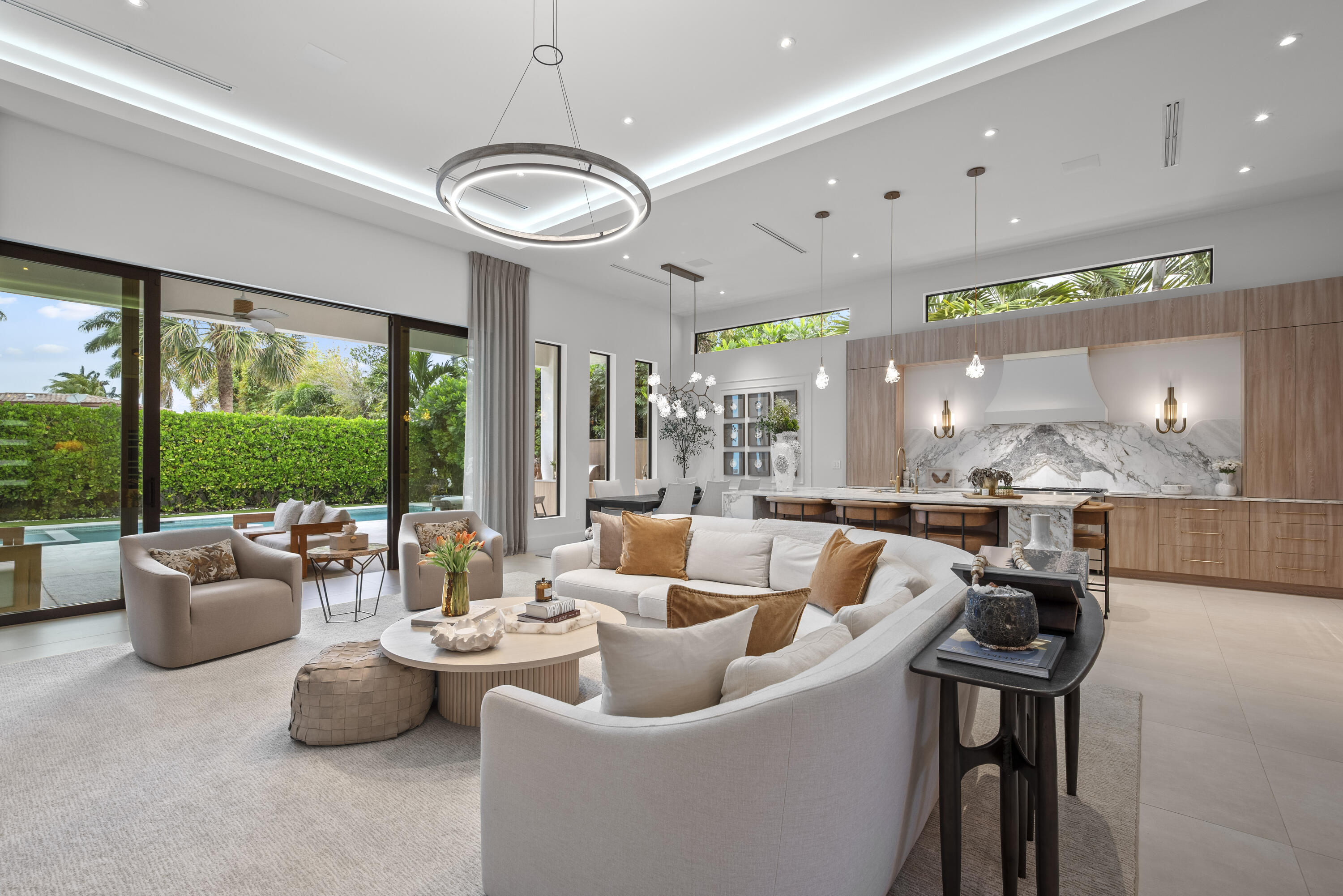 Experience refined luxury in this exceptional custom new-construction residence located in the heart of downtown Boca Raton.  Designed with meticulous attention to detail, this sophisticated home showcases bespoke finishes, cutting edge technology, and warmly curated spaces. A dramatic two-story foyer with soaring ceilings and a statement Shakuff chandelier sets the tone, leading into expansive open, living areas. The great room features a 10 foot linear fireplace with a quartzite surround and illuminated tray ceiling. The spectacular gourmet chef's kitchen is equipped with Wolf and Miele appliances, custom cabinetry, and a striking marble island and backsplash. A glamorous speakeasy bar adds both style and function, making this space truly unique. The dining area is conveniently located just off the kitchen, while floor to ceiling glass sliding doors create seamless indoor-outdoor flow, ideal for year round entertaining. The primary suite is a private sanctuary blending luxury and tranquility.  The spa inspired bathroom is a true showpiece featuring a custom floating vanity with dual sinks, expansive walk-in shower featuring two shower zones, soaking tub, exquisite marble finishes, and thoughtfully designed details. Completing the suite is a custom walk-in dressing room with illuminated display cabinetry and elegant accents offering both beauty and function in a boutique like setting.  Upstairs, a spacious loft with beverage bar is complemented by two additional ensuite bedrooms and a junior master suite. Outdoors, a private resort-style oasis awaits with a serene pool and spa featuring water and fire elements, upgraded summer kitchen ideal for dining alfresco, meticulous landscaping, outdoor shower and a dedicated enclosed dog run.  Additional highlights include full home automation, motorized shades, built-in speakers, video surveillance, generator gas line, prewire for elevator, custom white oak and glass staircase, large format limestone porcelain flooring on the first floor, and Riva white oak flooring upstairs. An additional side driveway and a finished garage with luxe pearlized epoxy floors and custom cabinetry create a spacious retreat ideal for car enthusiasts, storage, or a refined workspace. Ideally located just moments from Mizner Park, world-class dining, shopping, beaches, and parks, this extraordinary East Boca residence offers the perfect blend of modern elegance, comfort and walkable lifestyle.