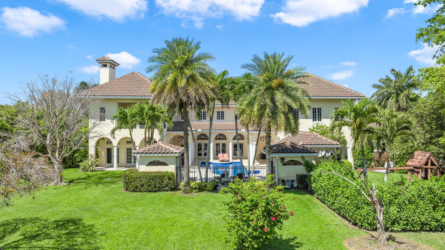 Nestled on 2.60 acres in the highly sought-after Paddock Park 2, this ultra-private two-story estate offers 7 bedrooms and 5.5 bathrooms with a thoughtfully designed layout ideal for family living, entertaining, and equestrian lifestyle. Set on a quiet street, close to Wellington International show grounds and with direct bridle path access this is an ideal property for equestrian use.  It features timeless interiors with mahogany floors, a chef's kitchen, maids quarters, gym, and expansive living spaces. Outdoors, enjoy a resort-style saltwater pool, full outdoor kitchen, lush privacy landscaping, and unique amenities including a basketball court, koi pond, and garden beds - all supported by top-tier upgrades like a new roof, full-house generator, impact glass, and advanced home systems. One of the largest single lots in the neighborhood allows plenty of extra room for a barn, equestrian features or other exterior features to suit your needs.  The residence showcases timeless design with rich mahogany wood floors, a classic and inviting aesthetic, and thoughtfully curated finishes throughout. The spacious layout includes custom upgrades throughout such as a dedicated home gym, chef's kitchen and an oversized gas fireplace that anchors the main living space. Car enthusiasts and families alike will appreciate the stately gated entrance leading to an impressive marble fountain and circular driveway, with an attached 3-car garage and additional 2-car garage.    The outdoor setting is surrounded by mature, designer landscaping with lush clusia and ficus hedges providing exceptional privacy. Enjoy resort-style living with a fully updated saltwater pool featuring new decking, a new heater, and refined finishes. The expansive outdoor kitchen is powered by propane and ideal for entertaining. Additional features include a half court basketball court with stadium lighting, koi pond, fountain, mango and guava trees, irrigated vegetable garden beds, electric dog fencing and even a dedicated dog house.    This property is equipped with top-tier systems for comfort and peace of mind, including a full-house generator, impact glass throughout, a new roof (2024), five A/C zones, clean-air UV lighting in all A/C units, reverse osmosis water system, attic decking for added storage, 7 inch seamless gutters, RV hookup with septic, and an ADT alarm and Ring camera system.    A rare opportunity to own a private, well-appointed estate in one of Wellington's most sought-after communities.