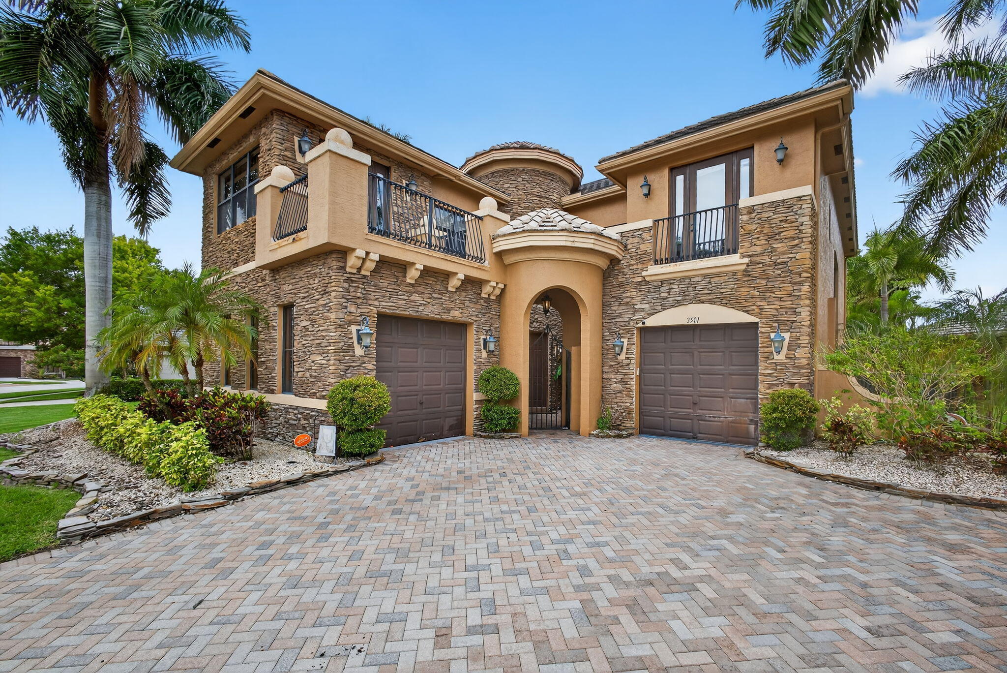 Experience luxury lakefront living in this highly desirable Moulin Rouge model, located within the prestigious, guard-gated Versailles community in the heart of Wellington. This expansive 4-bedroom, 4.5-bath pool home features a charming courtyard entrance, dual garages, and offers over 3,500 square feet of thoughtfully designed living space with an open layout ideal for both entertaining and everyday comfort. The gourmet kitchen is equipped with granite countertops, a center island, gas cooktop, double ovens, stainless steel appliances, and a dual sink with a window overlooking the backyard. Each bedroom features its own private en-suite bathroom and walk-in closet, with two bedrooms enjoying private walk-out balconies. Indulge in multiple elegant living spaces, including a grand formal living room, an impressive formal dining room perfect for hosting, a cozy yet spacious family room, and a sunlit breakfast nook framed by oversized windows that offer serene views of the pool and lake beyond. A generously sized laundry room adds everyday convenience. Ceramic tile flows throughout the first floor, while rich hardwood flooring elevates the second level.  Relax in the heated pool and overflow spa surrounded by lush tropical landscaping, all set on a premium fenced lakefront lot with southwest exposure so you can enjoy perfect breathtaking Florida sunsets. This corner lot offers serene lake views from both the backyard and the master bedroom. A paved circular driveway provides ample parking.  The Versailles community features resort-style amenities including a grand clubhouse, full gym, heated pool and spa, tennis courts, basketball courts, and a playgrounds. Ideally located near top-rated schools, restaurants, shopping, and just minutes from world-class polo clubs and equestrian venues. Lawn care, weekly pool service, and monthly pest control included. This home combines luxury, location, and lifestyle schedule your tour today!