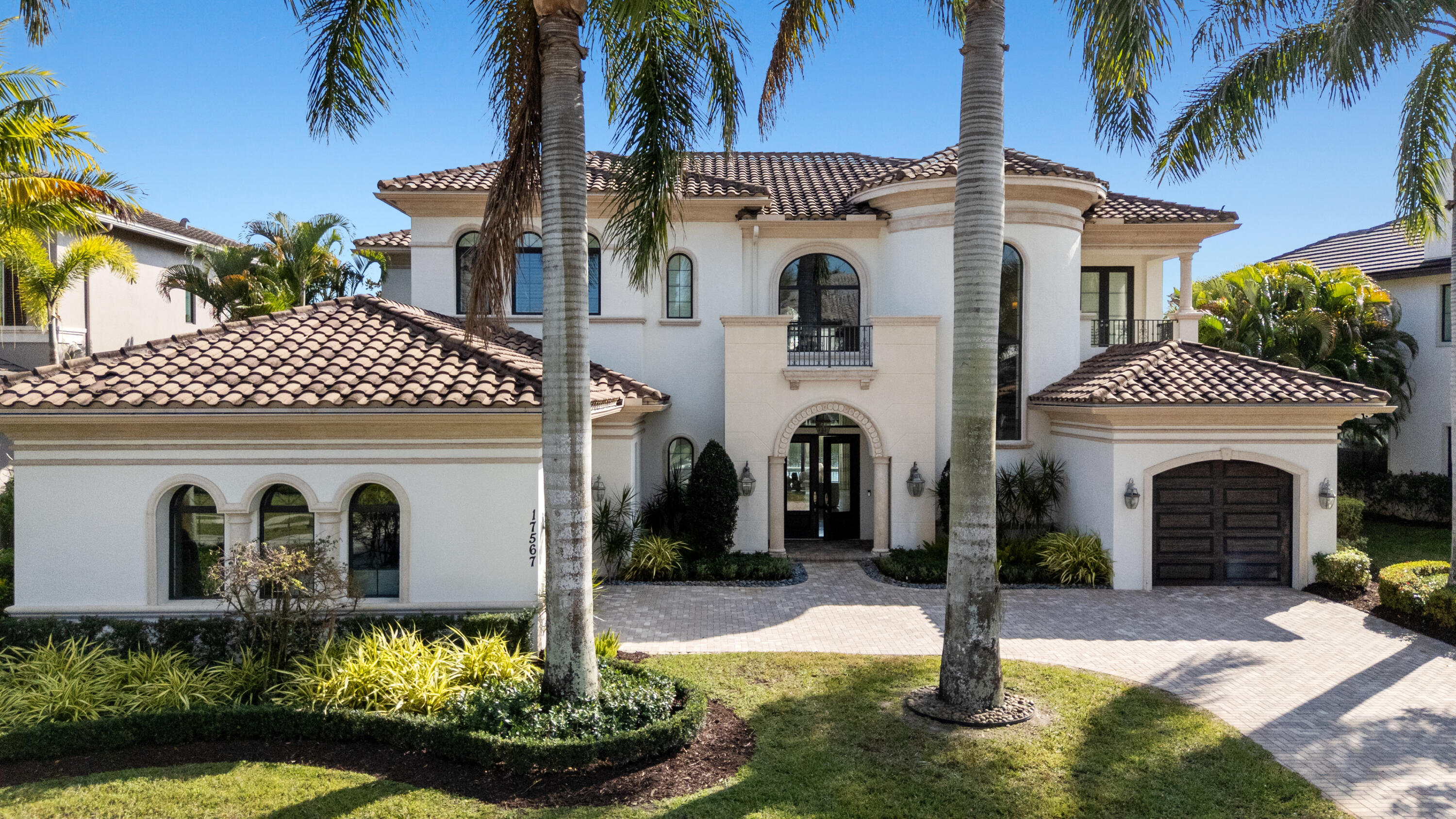 Meticulously designed and built in 2015, this exceptional lakefront estate embodies timeless elegance and modern luxury within The Oaks, one of Boca Raton's most prestigious gated communities.  Perfectly positioned on over a quarter acre of prime waterfront property, this exquisitely designed residence offers the ultimate blend of grandeur, comfort and functionality.  Featuring five ensuite bedrooms, six full baths, two half baths, a private office, media room, club room and loft, this home is thoughtfully designed for both everyday living and effortless entertaining.  A dramatic two story foyer sets the tone, welcoming you into interiors defined by refined architectural details and impeccable craftsmanship.  Stunning marble and rich wood flooring, bespoke millwork, custom window treatments and stunning wallpapers curated by a top local designer create a sophisticated yet inviting atmosphere throughout. At the heart of the home is a true chef's dream kitchen anchored by an expansive eat-in island and outfitted with top tier Wolf and SubZero appliances, including dual dishwashers and sinks, double ovens, side by side refrigerators and freezers and a wine refrigerator ensuring every culinary need is met. A walk in pantry is concealed by a barn door. Adjacent to the kitchen is a sunlit eat-in dining area and an expansive family room, which together create a warm yet sophisticated setting that truly becomes the heart of the home.
The home's grand scale living spaces flow seamlessly, all framed by breathtaking lake views. Designed with entertaining in mind the residence offers an inviting living room with incredible lake views and fireplace, a sophisticated club room, and a fully equipped media room with beverage refrigerator - the perfect setting for binge watching your favorite series or hosting unforgettable game day gatherings. The stately primary wing is a private sanctuary, introduced by double doors and a gallery style hallway with breakfast bar.  The luxurious suite offers a seating area, serene water views and a private balcony perfect to peaceful mornings or to watch the sunset. Dual spa inspired bathrooms and expansive custom closets provide both elegance and convenience.  Outdoor living is equally impressive and can be enjoyed all year.  A covered lanai seamlessly blends comfort and sophistication, featuring a fully equipped summer kitchen, retractable phantom screens, and an outdoor television.  Enjoy al fresco dining in the covered seating area  or relax on the sun deck beside the resort style pool and spa creating your own private oasis.  Additional premiums include a full house generator, impact windows and doors, Sonos sound system and Control 4 smart home automation for seamless modern living.