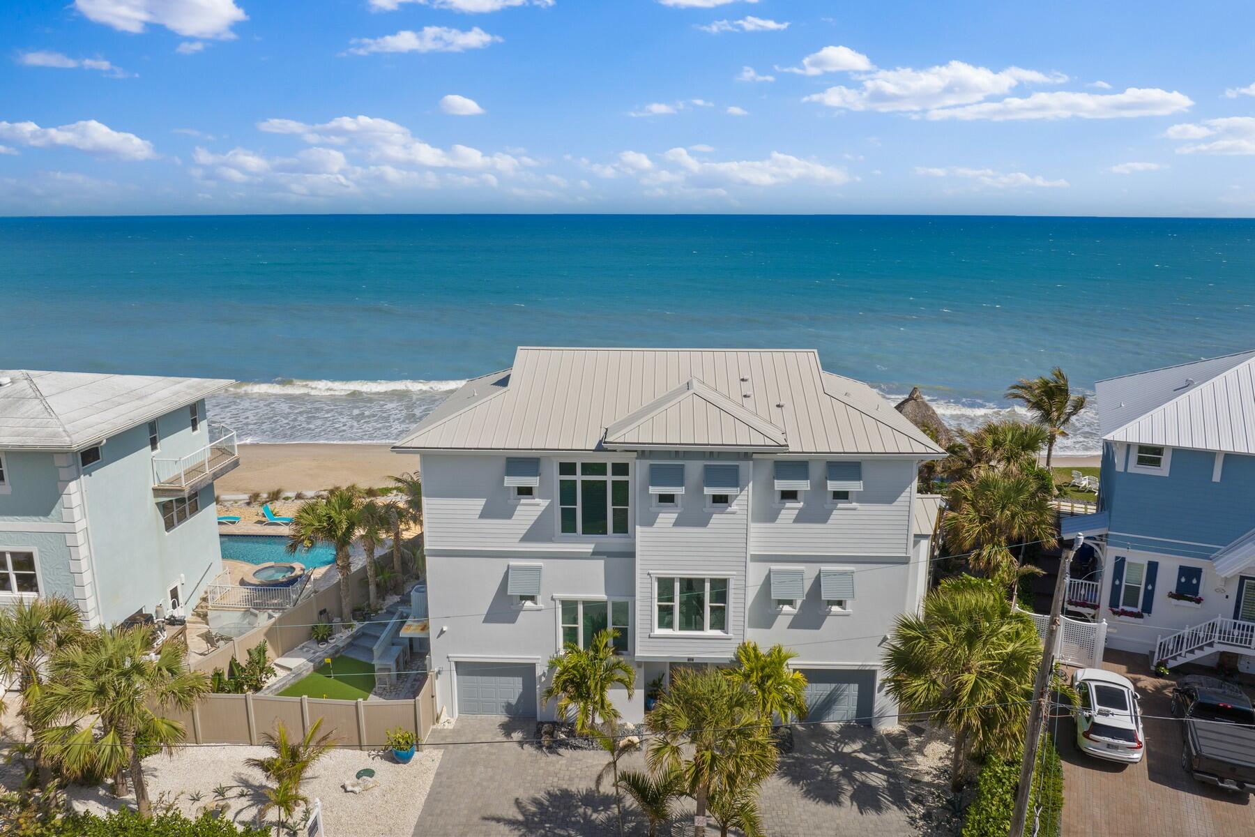 Experience unparalleled oceanfront living in this meticulously designed coastal retreat, nestled on an exclusive stretch of shoreline. Thoughtfully crafted by a renowned builder as their personal residence, this home blends modern innovation with timeless elegance to create a sanctuary of luxury and style.
Step through the grand foyer into the main living floor, where endless ocean views greet you from every vantage. The open-concept layout is anchored by a chef's kitchen that harmonizes form and function, featuring GE Monogram appliances, dual dishwashers, a Six-burner gas range, a wall oven/microwave, and a striking ocean-blue backsplash that mirrors the waves beyond. Main floor 4th bedroom and Office. Adjacent, an expansive deck with stainless railings invites seamless indoor-outdoor living, offering breathtaking vistas of lush landscaping and the Atlantic horizon.

On the third level, the primary suite is a serene haven with volume ceilings, and a spa-like bath complete with a soaking tub, double vanities, and a walk-in shower framed by custom glass. A private balcony extends the allure, providing a tranquil space to savor sunrises. Two additional guest bedrooms, including an en-suite, and a versatile loft space complete the upper floor, ensuring comfort and privacy for all.

Every detail of this home reflects thoughtful luxury, from plank tile floors and LED lighting to the smart Control 4 system that orchestrates programmable shades, lights, climate control,security and more. The outdoor spaces are equally impressive, with a summer kitchen featuring marine-grade 4 burner gas grill, a putting green, and a tiki hut overlooking the ocean. Maintenance-free landscaping with river rock gardens, and an irrigation system ensure effortless upkeep.

Built on pilings and fortified with a state-of-the-art seawall, this residence offers peace of mind, standing gracefully against the elements. Private beach stairs lead to a pristine shoreline, perfect for serene strolls or witnessing the marvel of sea turtle hatchlings.

With its sophisticated design, smart-home innovation, and breathtaking setting, this estate epitomizes coastal luxury. Don't miss the opportunity to own a one-of-a-kind oceanfront masterpiece that truly redefines the art of living by the sea.