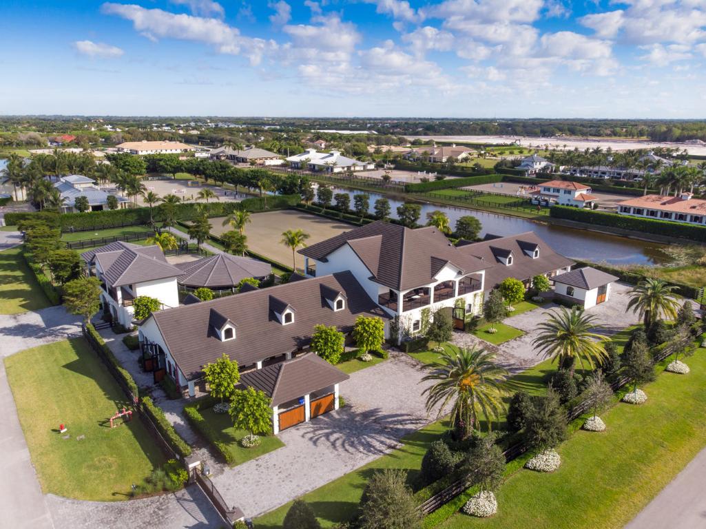 This stunning equestrian compound is located in the exclusive gated Grand Prix Village South community only a short hack to the WEF show grounds. The 20 stall stable on 4 acres includes luxurious owners quarters, large arena with premium footing, private vet/farrier clinic, laundry, storage, office, covered 4 horse walker, paddocks and large storage building with a large 2 bedroom staff apartment on the second level. The spacious tack room and owners lounge access the large covered patio with direct views of the arena. On the second level of the stables is the owners penthouse graced with 3 spacious bedrooms, center island kitchen and large bright living room with spacious balcony overlooking the property. This is a spectacular ''Must See'' equestrian property!!!