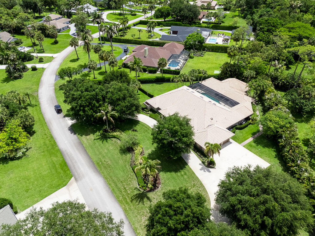 Nestled on a private 1.02-acre corner lot in the heart of Wellington, the Equestrian Capital of the World, this exceptional estate offers the freedom of no HOA restrictions and is zoned for all A-rated Wellington Elementary, Middle and High Schools. Ideally located just minutes from premier equestrian venues, fine dining, upscale shopping, and endless entertainment, this property combines luxury, privacy, and versatility in one remarkable package. The main residence features 4 Bedrooms, 4.5 Bathrooms, a 3-Car Garage, huge circular driveway, and 3,563 square feet, complemented by a 1,592-square-foot detached guest house with its own private entrance. Step into a light-filled interior with elevated ceilings, abundant skylights, recessed lighting, tile and wood flooring, plantation shutters, French doors, and elegant living spaces throughout. Entertain in the formal living room, multiple dining areas, and spacious family room complete with a custom bar and built-in shelving. Additional features include a whole-house generator, central vacuum system, coat closet, window treatments throughout, and newer air conditioning systems. The beautifully updated kitchen is designed for both everyday living and entertaining, featuring custom wood cabinetry, quartz countertops, a center island with cooktop, premium Wolf stainless steel appliances, double wall ovens, built-in microwave, Sub-Zero refrigerator, pantry, wet bar with sink, and a charming breakfast nook with a bay window overlooking the grounds. The oversized primary suite serves as a private retreat with tray ceilings, crown molding, plantation shutters, French doors leading to the patio, and a convenient coffee bar. The spacious handicap-accessible ensuite bath offers dual vanities, quartz and granite countertops, custom wood cabinetry, a large walk-in shower, private water closet, and bidet. Outside, the property transforms into a resort-style oasis. Enjoy complete privacy with a fenced sideyard, mature professional landscaping, circular driveway and additional parking slab perfect for an RV, boat, or recreational vehicle. In the courtyard, relax in the heated saltwater pool and spa, entertain under the screened and covered courtyard-style patio, or host gatherings at the fully equipped summer kitchen featuring a grill, water, electric service, beer tap, and outdoor speakers. Additional exterior features include partial hurricane-impact doors, impact garage door, underground gas tank, gutters, septic system, and pool safety fencing. The detached guest house offers incredible flexibility with a kitchenette, living area, a bedroom, gym, cabana bath,  movie theater, permanent generator, and private entrance—ideal for guests, multigenerational living, a home business, or extended stays.  Truly, a rare opportunity to own a private estate in one of South Florida's most sought-after locations with the freedom of no HOA restrictions.