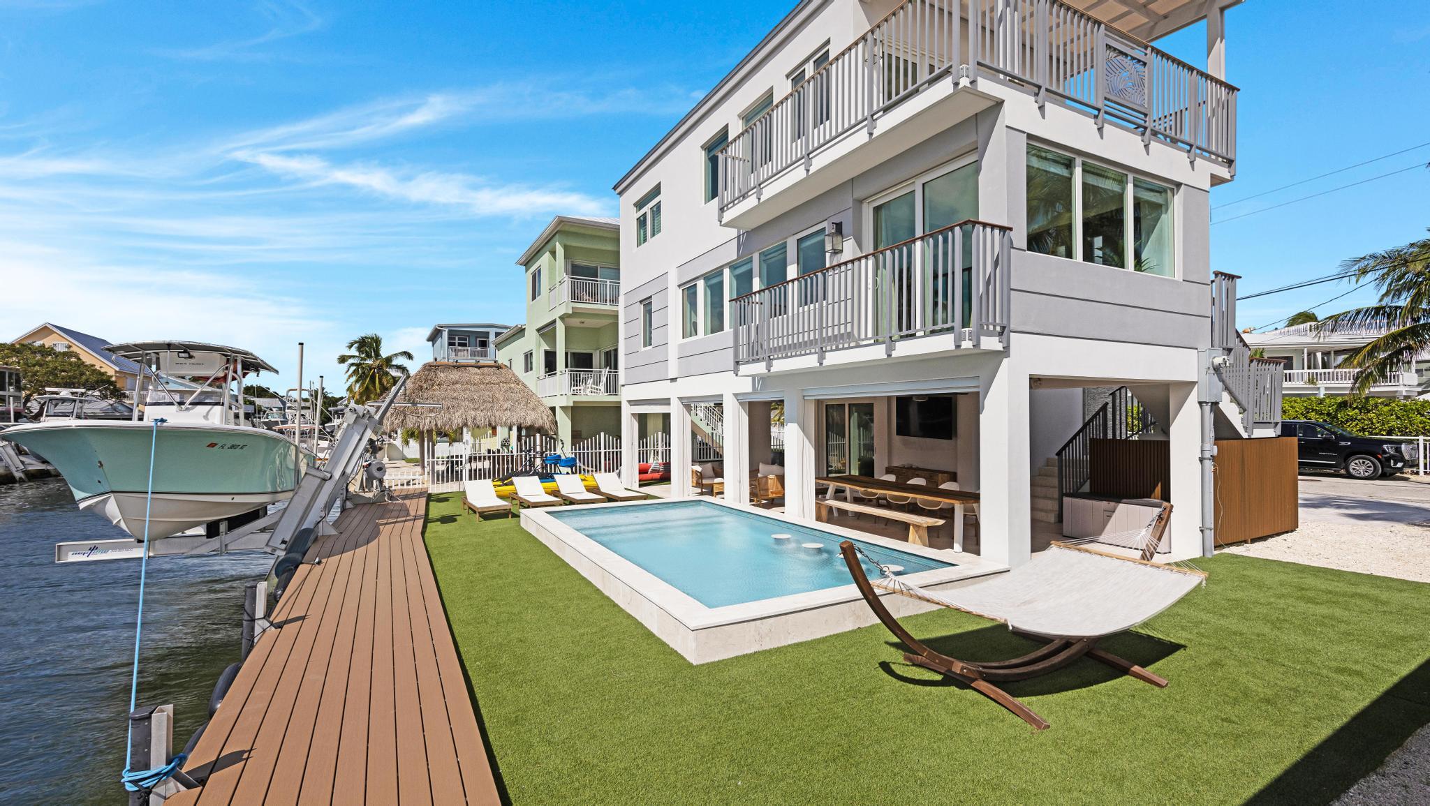 Wake up on the water in this turnkey, fully furnished coastal retreat in the heart of Key Largo. Complete with a modern, beach-chic design, this 3-bedroom, 3-bath home blends effortless luxury with true Florida Keys living. Outside, enjoy direct ocean access from your private dock with boat lift--just minutes to world-class fishing, diving and sandbars. After a day on the water, unwind in the resort-style pool with submerged bar stools, sun shelf, and turf yard perfect for lounging, grilling, and sunset cocktails. Walls of glass and multiple balconies frame sweeping ocean and canal views, filling the home with natural light. The open-concept main level features a stunning chef's kitchen with sleek cabinetry, quartz waterfall island, Bosch appliances, and gold accents, flowing into a  relaxed living area designed for entertaining. The spacious primary suite is a true sanctuary with panoramic water views, private balcony, and spa-like bath boasting a freestanding soaking tub, oversized glass shower, and designer finishes. Guest rooms are thoughtfully furnished--including a bunk room--offering comfortable accommodations for family and friends. Offered fully furnished, down to the décor, this home is truly move-in ready--ideal as a primary residence, vacation escape, or high-end rental property. Experience the best of Keys waterfront living with style, comfort, and unbeatable ocean views