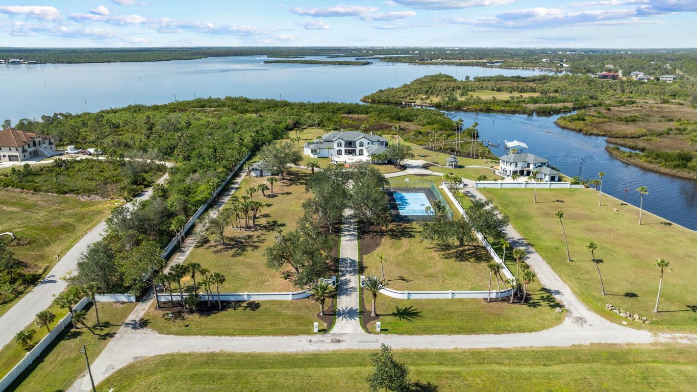 Welcome to The Magic on the Myakka! No expense was spared in creating this masterpiece. Every inch of the home has been beautifully upgraded and well-considered. Situated on 20 ACRES of privacy with unobstructed views of the MYAKKA RIVER. Concrete seawall hugs the perimeter of the waterline and with deep waters, you have minimal limitations due to vessel size. Short cruise to the open waters of Charlotte Harbor and then off to the Gulf of Mexico. As you enter through the gates and meander down your private lane past the TENNIS COURT, you will be in awe at first sight. The property is meticulously maintained and the attention to detail shows. With just under 9,000 SQ FT OF LIVING SPACE, you find the layout of the main home is well designed for functionality. As you enter you will take a pause just to take it all in. You will need to walk the home at least twice because many of the fine details may be missed at first glance. The space is blanketed in natural light streaming from the countless WINDOWS, all of which have been upgraded to ENERGY EFFICIENT, IMPACT. Further peace of mind with a WHOLE HOME GENERATOR. The main living area lies straight ahead and provides a gorgeous view of the pool. Even the most discerning in the culinary realm will not find fault with this kitchen. In addition to the aesthetics, this space features a butler's pantry, 8 BURNER GAS RANGE with grill top, quartz counters, expresso cabinetry, and counter seating for six. Enjoy meals in the dining area looking out to the water. Pass through the family room and past the THEATRE ROOM, billiards room, VEGAS ROOM, and bar to the master suite. We need to pause again and draw your immediate attention to the picture of "her" closet. You cannot help but be inspired. The master suite opens to a private patio and has a spiral staircase leading to the loft, which takes the phrase office with a view to the next level. The upstairs features 3 additional bedrooms, each with ensuite baths, extended closet space and balcony access. Let's be honest, most of your time will be spent outside. Intimate time with the family or hosting a large gathering, this is the perfect setting. Your grass will always look great with maintenance free turf. Designed for a functional kitchen, the covered sitting area is perfect for entertaining. The SALTWATER POOL was completely remodeled and features ON DEMAND HEATING. Relax in the loungers on the sun shelf. Sunken seating and fire pit. As the sun sets, the FIRE BOWLS and torches will glow creating an ambience you find only at the most exclusive resorts. Follow through the gazebo to the 2700 SQ FT GUEST HOUSE. The views are breathtaking, and the options are endless here. Kitchen space on both levels. Comfortable living room and dedicated dining area downstairs and three bedrooms/2 baths upstairs. Bring the toys, because there is plenty of garage space available. Car collectors will appreciate that the GARAGES ARE TEMPERATURE CONTROLLED. This 20+ acres estate includes 8 vacant adjacent lots ready for any investment venture. This is a once in a lifetime opportunity to purchase your dream home and not change a thing. Please reach out for an expanded list further describing the upgrades and features, including all new roofs. The tasteful DECOR REMAINS creating a space that is move in ready. This property presents a lucrative opportunity for further development into a waterfront community with the right vision. Preliminary footwork is available. This estate is magical and must be viewed in person to appreciate all the nuances.