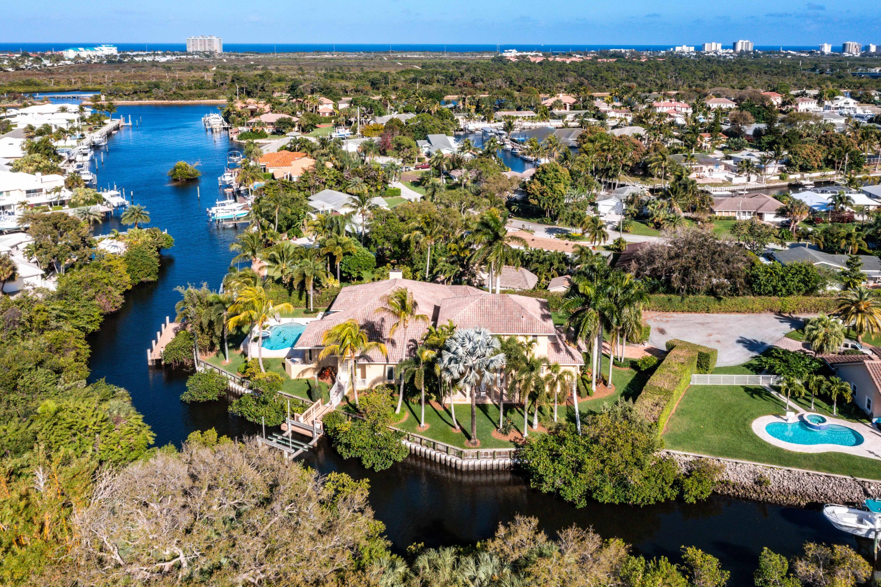 This magnificent custom home offers waterfront privacy in a small, gated community of only five homes in the unincorporated enclave of Little Cypress Pointe situated between Jupiter and Palm Beach Gardens. The home was built in 2000 by the current owners and is less than 5 minutes from the Beaches, the Juno pier, Jupiter Hospital, the Gardens Mall and all the best restaurants and shops in the Palm Beach Gardens, Juno Beach and Jupiter area. The home is on .87 acres and features approximately 255 feet of water frontage on two sides with a boat dock and a separate 25,000 pound boat lift on Little Cypress Creek. The property also includes a separate, potentially buildable parcel of .11 acres with 162 feet of waterfront that was left as a natural preserve by the owners to ensure the maximum privacy of the home. This one of kind property combines privacy, calm waters and excellent hurricane hole protection for a 40+ foot boat with direct Intracoastal to Ocean access and no fixed bridges. From your backyard dock, you are just two minutes by boat to the Intracoastal Waterway at idle speed or you can canoe and paddleboard the protected waters of the Creek and connecting canals.

The two story home is approximately 5,500 square feet under air and over 7,000 total square feet with 4 bedrooms, five full baths, an oversized three car garage and impact glass doors and windows throughout.  Entering through the custom iron doors into the living room with a soaring 16 foot ceiling and a beautiful gas fireplace, and magnificent view of the pool and dock. The main living area also includes a library, formal dining room, family room, wet bar with icemaker, refrigerator and wine cooler, a chef's kitchen and a full cabana bath directly accessible from the boatlift. 

The chef's kitchen includes a built-in Monogram refrigerator/freezer, Sub-Zero 150 bottle wine cooler, Thermador 4 burner gas rangetop with griddle and stainless steel range hood, KitchenAid double ovens, Bosch dishwasher and microwave drawer in the expansive kitchen island. The kitchen boasts tons of storage in the cherry wood cabinets with granite counter tops and the large double door pantry. A second refrigerator/freezer is located in the laundry room with the Samsung washer/dryer and additional storage.

The split floor plan includes the Owner's Suite and 2 ensuite bedrooms overlooking the water on the ground floor. The Owner's Suite includes a large master bath with double shower heads and a rain shower, a jetted soaking tub, separate his/her vanities and water closets, a private office/gym, two large walk-in closets and the Master Bedroom which overlooks the pool, patio and dock. All bedrooms have walk-in closets with custom closet shelving systems. The air conditioning system is divided into 3 zones for the Owner's Suite, main living area and second floor.

The second floor guest suite is above the garage and consists of a spacious family room/game room with pool table, a bar/kitchenette that could be updated to a full kitchen and an ensuite bedroom with walk-in closet. The family room/game room opens onto a large second floor deck that overlooks side yard, the water and beautiful sunsets. The oversized 3 car garage includes three individual 9 x 9 hurricane rated garage doors making all your toys easy to access and store while also keeping your cars in the garage. The garage also includes a solid, poured concrete, hurricane safe room and with 11 foot ceilings, it could easily accommodate lifts for storing additional cars and toys.

The lushly landscaped yard with water on two sides provides you with security, peace and privacy from your neighbors while offering plenty of room for entertaining with a new summer kitchen, an open air dining area on the pool and spa deck with gas tiki torches and a covered outdoor patio/dining area. The covered patio also has a rolldown hurricane screen to provide secure storage for your outdoor patio furniture and accessories in the event of a storm. The pool and spa have a saltwater chlorination system and two speed pump for low maintenance, with a gas heater to allow for year-round use. All the indoor and outdoor gas appliances are supplied by a 500 gallon tank buried in the front yard. The house has wired and wireless security camera systems that are internet accessible and motion activated floodlights on the entire perimeter of the roof.