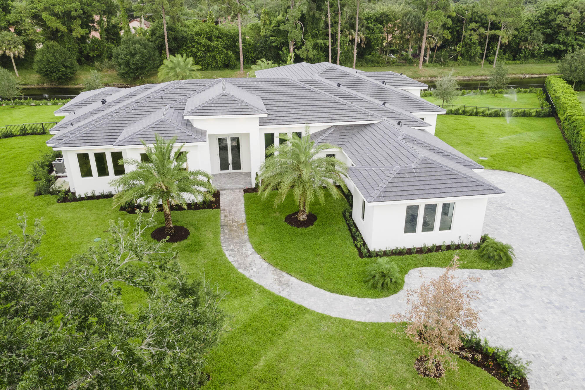 Set on a sprawling home site in Steeplechase, one the most prestigious gated neighborhoods in Palm Beach Gardens, you will find serenity redefined. This brand new custom estate home is fully built and move-in ready. A modern masterpiece on a private 1 acre lot with 5 bedrooms, 7 baths + office/club room, 3.5 car garage, and over 5,000 sq ft. This elegant design features huge 14ft volume ceilings, modern open layout that provides seamless transitions from the main living area to the other sections of the home. The incredible level of detail and ultra high end finishes puts this property in a league of its own. In the spacious gourmet kitchen you'll find Italian porcelain flooring, double waterfall quartz countertops, custom European cabinetry, and top of the line Sub-Zero & Wolf Appliances.