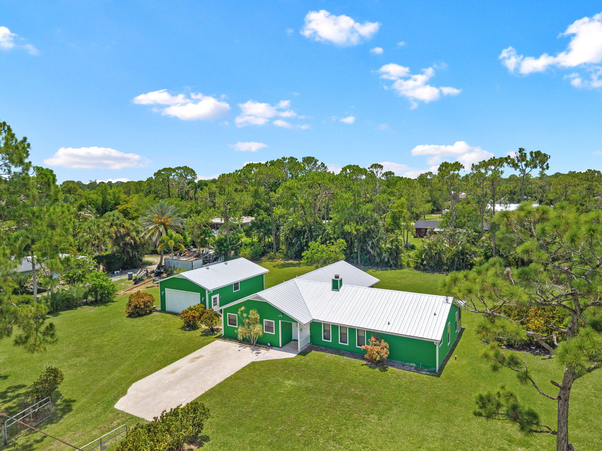 Discover the charm and character of this custom-built cedar home situated on a spacious lot in desirable Loxahatchee. HUGE DETACHED GARAGE - BRING THE TOYS! Constructed with durable 6-inch frame walls and designed for energy efficiency, this home offers the perfect blend of rustic warmth and modern functionality.  Inside, you'll find 2,304 living square feet featuring 4 bedrooms and 3 full bathrooms in a desirable split-bedroom floor plan that provides privacy and flexibility for families or guests. Vaulted ceilings create an open and airy feel, while hardwood flooring in the kitchen and family room adds warmth and timeless appeal. Gather around the cozy fireplace or enjoy the abundance of natural light streaming through energy-efficient double-pane windows. Step outside to a large 1.15-acre lot, fenced backyard surrounded by privacy hedges, offering plenty of room for entertaining, pets, or future additions—with no pond to limit usable space. Car enthusiasts, hobbyists, and outdoor adventurers will appreciate the oversized detached garage with workshop, providing ample space for vehicles, equipment, and toys.  Additional highlights include a brand-new metal roof installed in 2025, excellent schools, and a prime Loxahatchee location with easy access to shopping, dining, and major roadways. This one-of-a-kind property combines privacy, functionality, and character in a setting you'll love to call home.