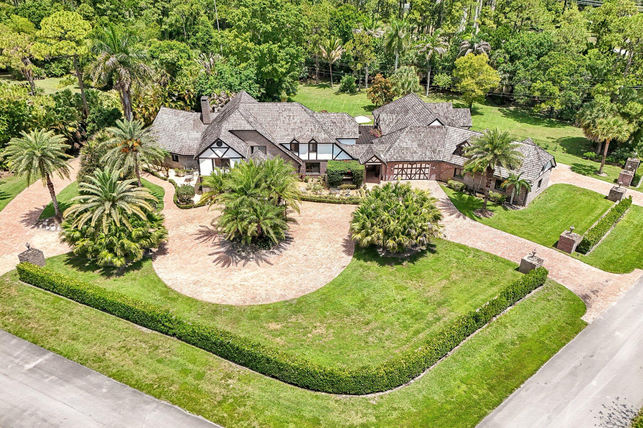 Nestled on over 2.3 pristine acres in the highly sought-after Wellington community of Paddock Park, this English Tudor estate is a true masterpiece of craftsmanship, elegance and modern luxury. This remarkable compound blends timeless architectural character with exceptional upgrades throughout. The compound is secure with complete impact windows and doors. A whole house generator and reverse osmosis system. The Main home features 4-bedroom and 4-bathrooms; complementing the main home is a 3-bedroom, 3-bathroom guest house offering privacy for guests, staff, or multigenerational living. For the automotive enthusiast, the property boasts an impressive 7-car garage designed to accommodate a premier car collection. Saltwater pool and heated spa offer year-round resort living.