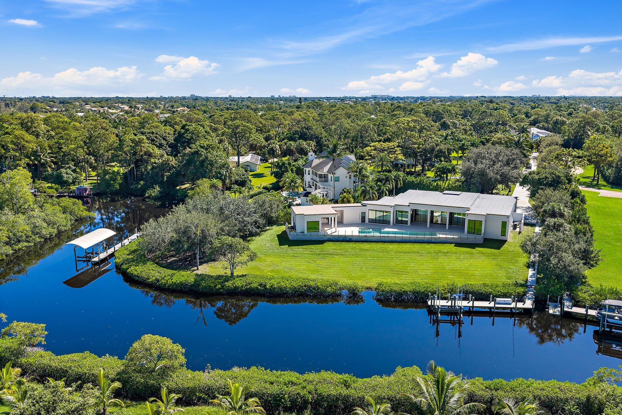 Newly completed in 2025, this exceptional waterfront estate sits on over two private acres along the North Fork of the Loxahatchee River. Thoughtfully designed with clean architectural lines, curated finishes, and seamless indoor-outdoor living, the residence offers a rare combination of modern construction and expansive grounds--recently repositioned to $6,495,000. The home features four bedrooms and four-and-a-half baths with soaring ceilings and walls of glass that frame tranquil river views. The chef's kitchen is appointed with a Wolf range, Miele built-in coffee system, Subzero fridge and wine fridge, custom cabinetry, and an oversized island designed for entertaining. Open living and dining spaces flow effortlessly to covered outdoor areas, creating a year-round waterfront lifestyle The primary suite is privately situated and offers serene views, a spa-inspired bath, and generous custom closets. Each guest suite is well-proportioned and en-suite, providing comfort and privacy for family and visitors alike. Outdoors, the scale of the property allows for privacy rarely found on the river. The expansive grounds offer room for future enhancements--guest house, sport court, or additional recreational amenities--while maintaining a secluded estate setting. A private dock with 16,000-pound lift provides convenient boating access with one fixed bridge to the Intracoastal. Whether enjoying quiet mornings on the river or entertaining at sunset, this property captures the essence of Jupiter waterfront living. A recent land acquisition in the neighborhood of similar size traded for $3.3 million, making this completed home a smart investment. An uncommon opportunity to secure new construction, acreage, and boating access in one of Jupiter's most desirable waterfront corridors.