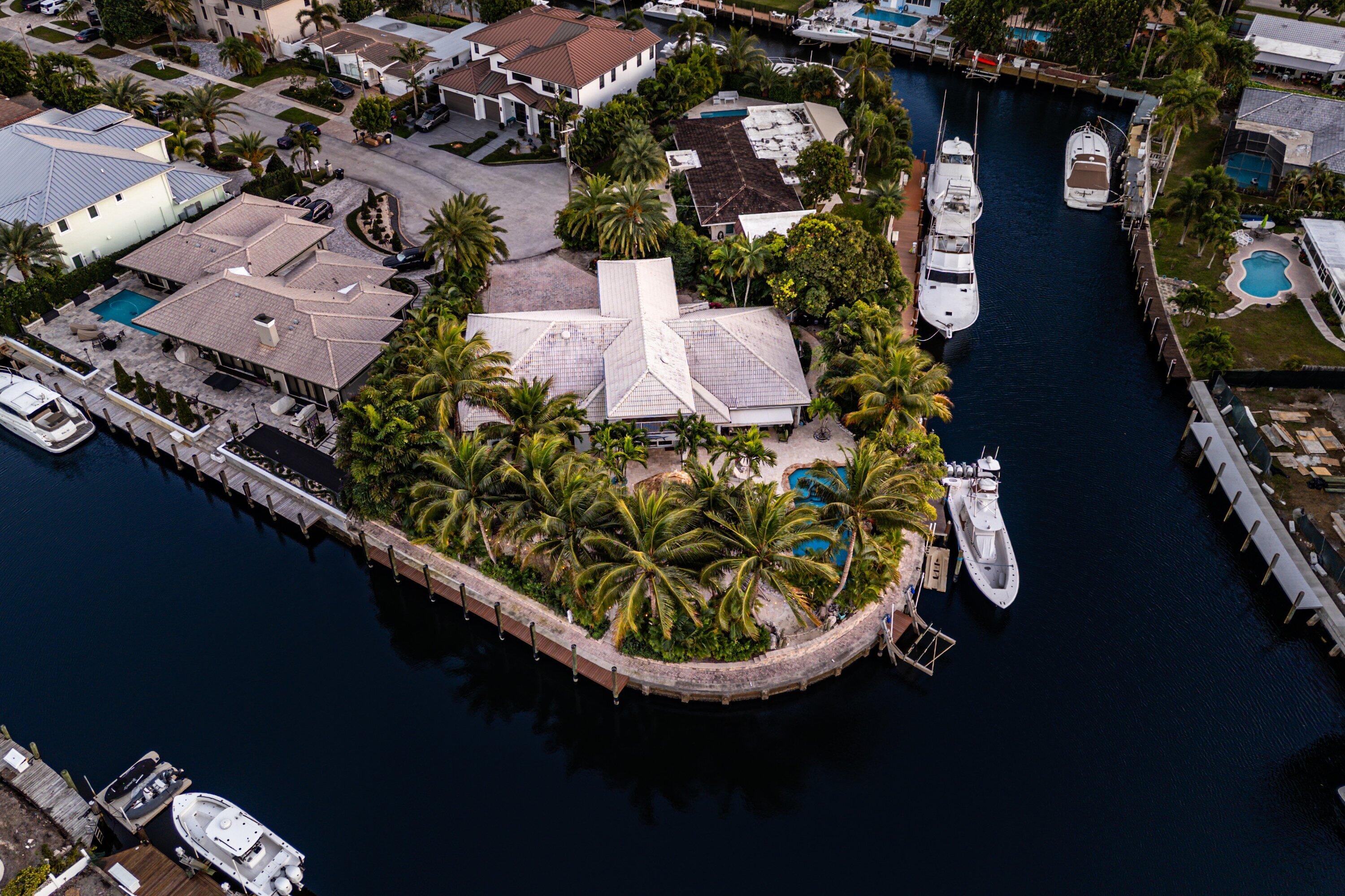 An exceptional 4-bedroom, 4-bath residence set on an impressive 242 feet of waterfront frontage, positioned on a premier point lot—one of the largest currently available in Lighthouse Point. This stunning home showcases a spacious open-concept layout with soaring volume ceilings, a grand chef's kitchen, and seamless indoor-outdoor living. The resort-style exterior features a grotto-inspired pool, ocean-view spa, lush tropical landscaping, and a private, oasis-like atmosphere ideal for entertaining. Perfectly located with direct ocean access and breathtaking panoramic water views from every angle.
