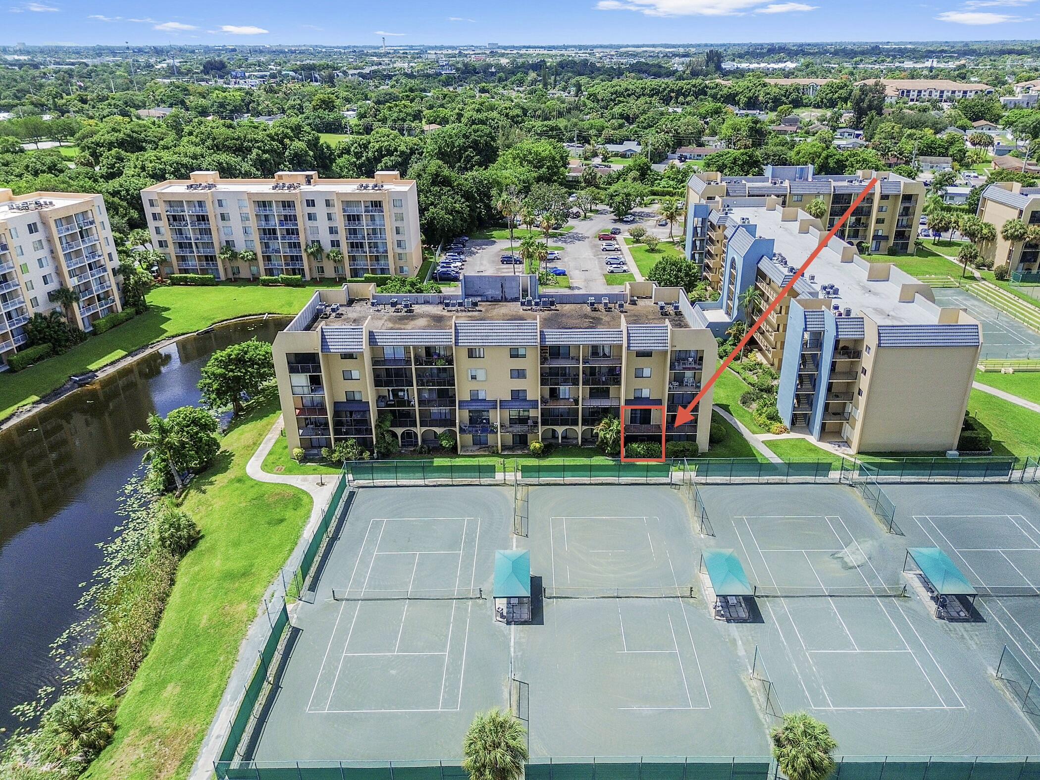 Stylishly updated 2-bedroom, 1.5-bathroom corner unit in the desirable Tennis Club of Palm Beach. This unique townhouse-style condo offers 1,068 sq ft of living space across two levels with a modern, move-in-ready feel throughout.  The upper level features a foyer entrance that opens to a spacious open-concept living and dining area with large-format tile flooring, designer accent walls, decorative architectural ceiling details, recessed and track lighting, and sliding glass doors leading to an open balcony with charming brick pavers and stunning views of the tennis courts. The renovated kitchen boasts sleek two-tone cabinetry, white quartz countertops, a subway-tile backsplash, and KitchenAid stainless-steel appliances.    An updated half bath with subway tile and modern black fixtures completes the upper level.  The lower level offers two bedrooms with ambient LED accent lighting and built-in closet shelving, including the master with dramatic wall-wash lighting, tile flooring, and sliding glass doors opening to a private enclosed patio with lush privacy greenery. The full bathroom features a generous vanity, eye-catching aqua mosaic tile flooring, and a subway tile tub/shower surround. An in-unit stacked washer and dryer adds everyday convenience.  The Tennis Club of Palm Beach is a premier lakeside community featuring 20+ lighted tennis courts, a resort-style community pool, a clubhouse, scenic lakes with fountains, and lush tropical landscaping. Conveniently located near shopping, dining, beaches, and major roadways.