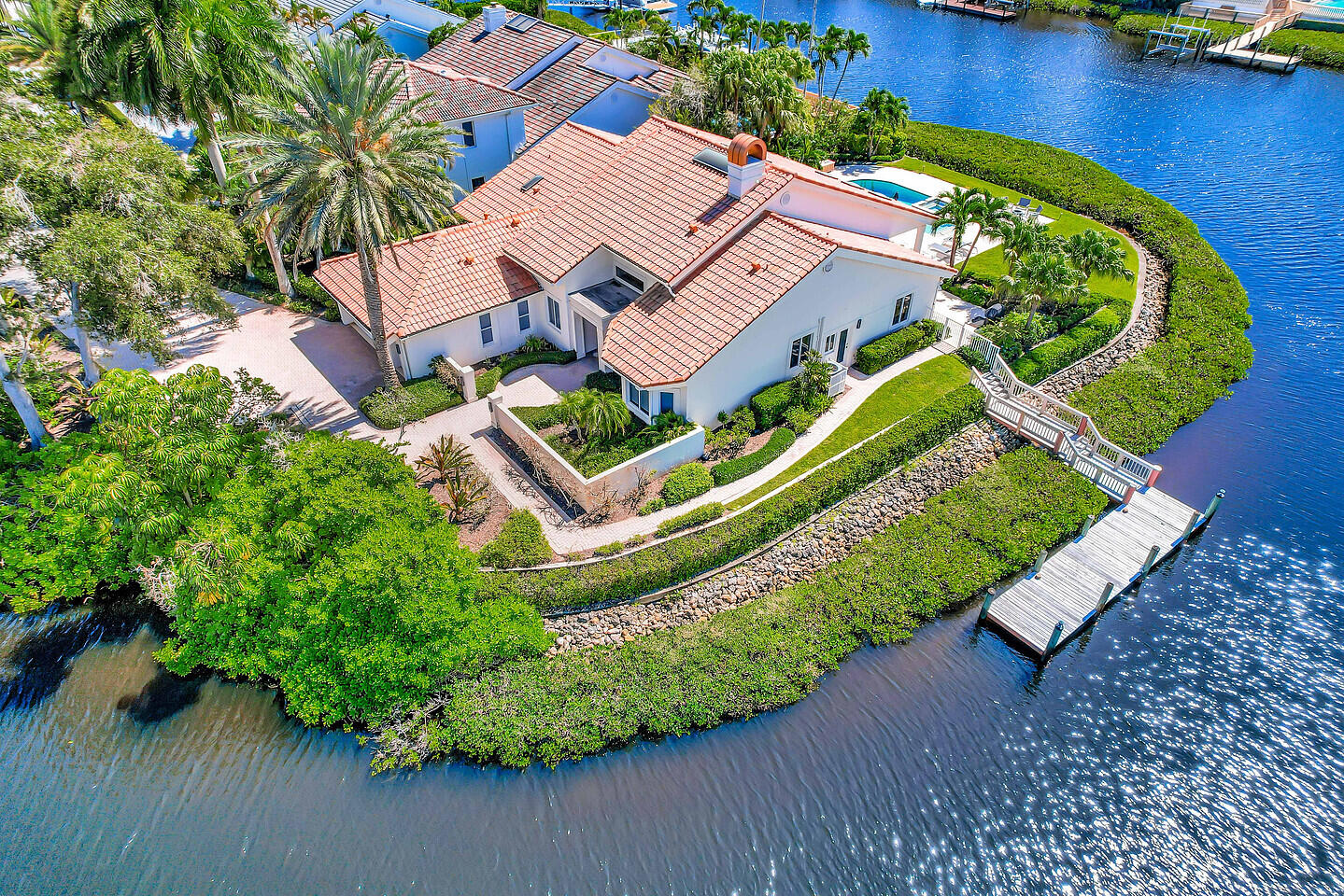 Your dream home in Admirals Cove awaits! This rare point lot offers 300 feet of waterfront with breathtaking views on three sides, including spectacular southwest sunsets. Completely and tastefully remodeled, the residence showcases a timeless transitional design with an open floor plan. Inside, you'll find four bedrooms, each with its own en suite bath, plus a powder room. Finishes include French oak wood floors with a herringbone-pattern foyer, a cathedral tongue-and-groove ceiling, a floor-to-ceiling marble fireplace, Lutron lighting, and impact windows. The gourmet kitchen features Carrara marble countertops, JennAir appliances, double ovens, a six-burner gas cooktop, and a wine cooler. Enjoy the serene outdoor living areas in total privacy from your pool, spa, and multiple seating... areas across nearly a half-acre of lush grounds. The lot can accommodate a boat up to 65 feet, offering easy access to the Intracoastal with no fixed bridges. This exceptional property also offers opportunity for expansion.  Required golf membership purchase conveys all the first class amenities of Admirals Cove including two spectacular clubhouses, 45 holes of golf, 5 restaurants, 58 slip marina with floating docks, Yacht Club, 9 har tru tennis courts, 12 pickleball courts, state of the art fitness and wellness center with Technogym machines, 21,000 sq ft spa & salon, 30 room Waterside Private Boutique Hotel for members and their guests, brand new Golf Learning Center, Covesters kids club, dog park and Platinum service.