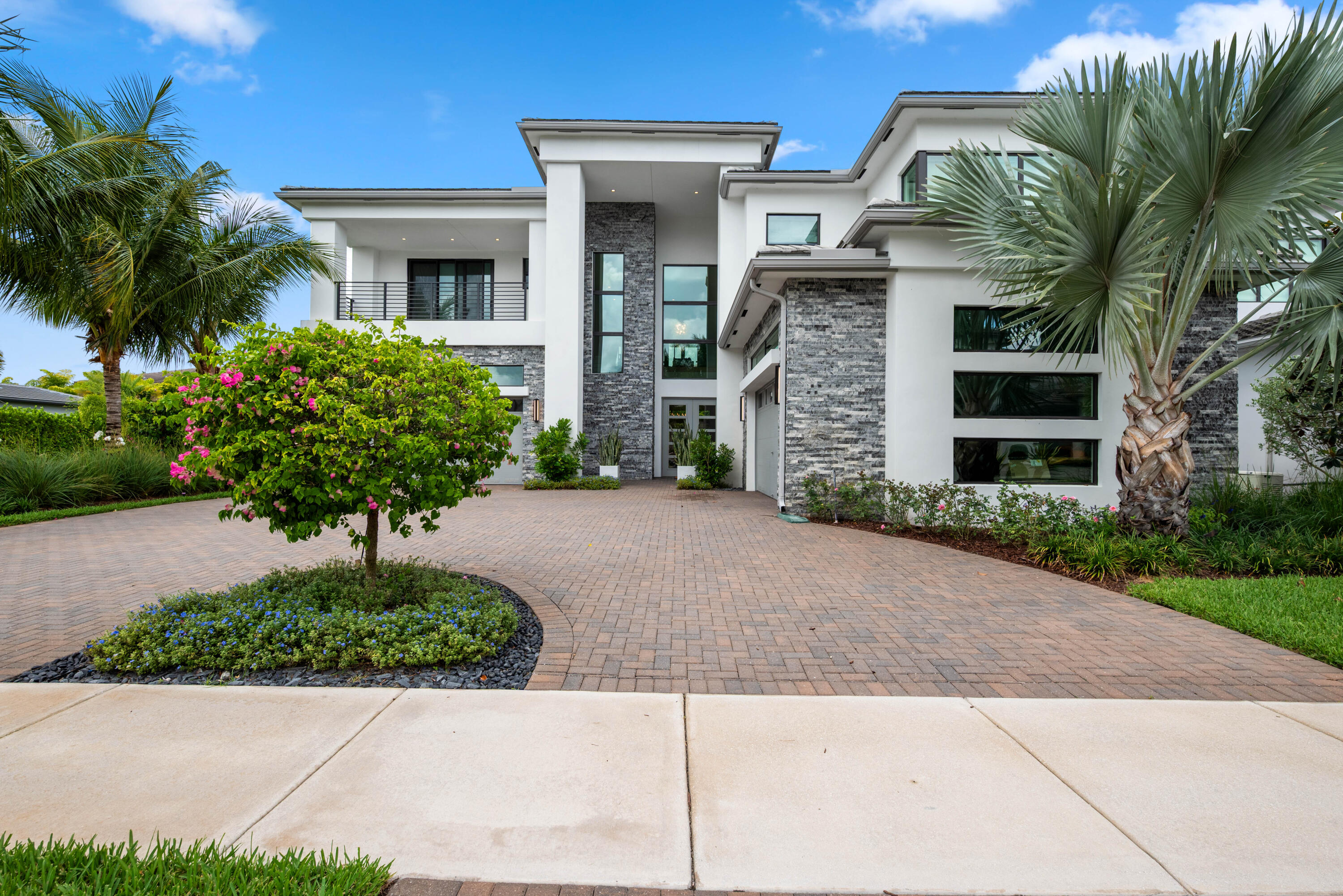 Welcome to a custom-designed turnkey Riverside model in the Coastal section of Boca Bridges, offering refined luxury and effortless move-in-ready living. This exquisitely designed residence blends grandeur, comfort, and functionality. Featuring five ensuite bedrooms, six full baths, one half bath, club room, and loft, the home is thoughtfully designed for both everyday living and effortless entertaining. A dramatic two-story foyer sets the tone with light oak engineered hardwood floors flowing seamlessly throughout, complemented by custom millwork, architectural archways, and designer accents. At the heart of the home is a chef's kitchen anchored by an expansive eat-in island and outfitted with top-tier Wolf and Sub-Zero appliances. Adjacent is a sunlit dining area and expansive family  room, creating a warm yet sophisticated space ideal for entertaining, or realxing.  The primary suite serves as a private sanctuary with a seating area, custom window treatments, and designer lighting. Spa-inspired baths and expansive custom closets elevate both luxury and functionality.  Outdoor living features a custom pool and spa, turf landscaping, and a private putting green. A rare turnkey opportunity in Boca Bridges offering elevated design and an exceptional lifestyle.