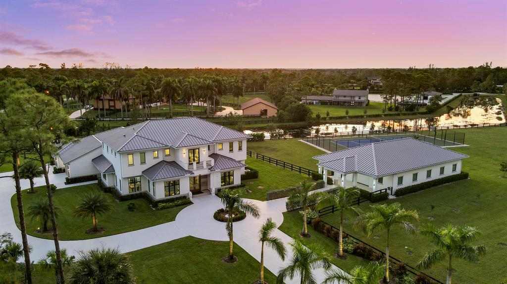 Gorgeous Custom Estate Home located on over 5 acres in the highly sought-after Equestrian Community of Homeland. This 5 Bed 6.5 Bath 2020 construction looks and feels brand new. The main home features 12' high ceilings, custom millwork, wood/tile floors, grand spiral staircase with elevator alternative. Enjoy two primary owner's suites, one on each level. Both suites include custom his/her closets/bathrooms, large window views, and breakfast bars. In addition, there is a 3000 Sq Ft climate-controlled garage/showroom/workshop for your prized collections (or can be easily converted back to 10 stall center isle stable). Peace of mind is guaranteed by full impact doors and windows, whole house generator (powered by 1000 gallon propane tank), and whole house RO water system. Fully equipped gas-fire summer kitchen sits next to salt-chlorinated pool and spa. Owners and guests will love the gorgeous views and plenty of patio space overlooking the garden and tennis-basketball sports court. Backyard provides room for building a private go-cart course, 3-hole mini golf, or a private lake. This luxury home built for the future offers a 4-car garage pre-wired for TWO level 2 charging stations. Schedule your private viewing to see this stunning paradise today.