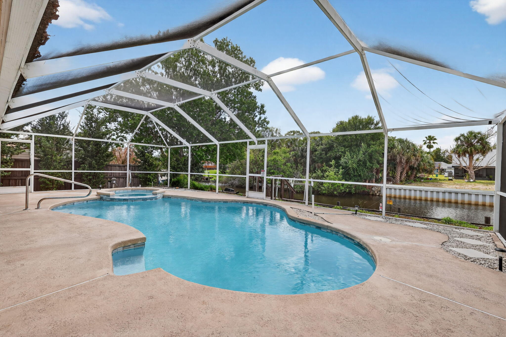 OCEAN ACCESS! POOL! Welcome to Old Florida living at its finest. This waterfront home offers direct ocean access via canal, complete with a seawall and dock. Nestled on a quiet cul-de-sac peninsula, it minimizes through traffic and delivers a peaceful, private neighborhood feel. The fully fenced backyard features mature fruit trees and a beautifully refurbished saltwater gunite pool (2024) inside a spacious screened enclosure — creating the perfect private oasis for relaxing or entertaining. Inside, the major updates are complete: New 2024 roof with current wind mitigation certification New 2024 AC system, New tile flooring (2026) Impact-resistant windows and doors throughout. The open-concept layout features a split-bedroom design, vaulted ceilings, and abundant natural light. Additional OCEAN ACCESS! POOL! Welcome to Old Florida living at its finest.  This waterfront home offers direct ocean access via canal, complete with a seawall and dock. Nestled on a quiet cul-de-sac peninsula, it minimizes through traffic and delivers a peaceful, private neighborhood feel.  The fully fenced backyard features mature fruit trees and a beautifully refurbished saltwater gunite pool (2024) inside a spacious screened enclosure — creating the perfect private oasis for relaxing or entertaining.  Inside, the major updates are complete:  New 2024 roof with current wind mitigation certification New 2024 AC system New tile flooring (2026) Impact-resistant windows and doors throughout The open-concept layout features a split-bedroom design, vaulted ceilings, and abundant natural light. Additional highlights include an epoxy-coated garage floor and a versatile den/office space.  This move-in-ready gem offers 3 bedrooms, 2 full baths, and approximately 1,940 square feet of living space. With the heavy lifting already done, this thoughtfully updated waterfront retreat is ready for its next owner.  No HOA • Not in a flood zone