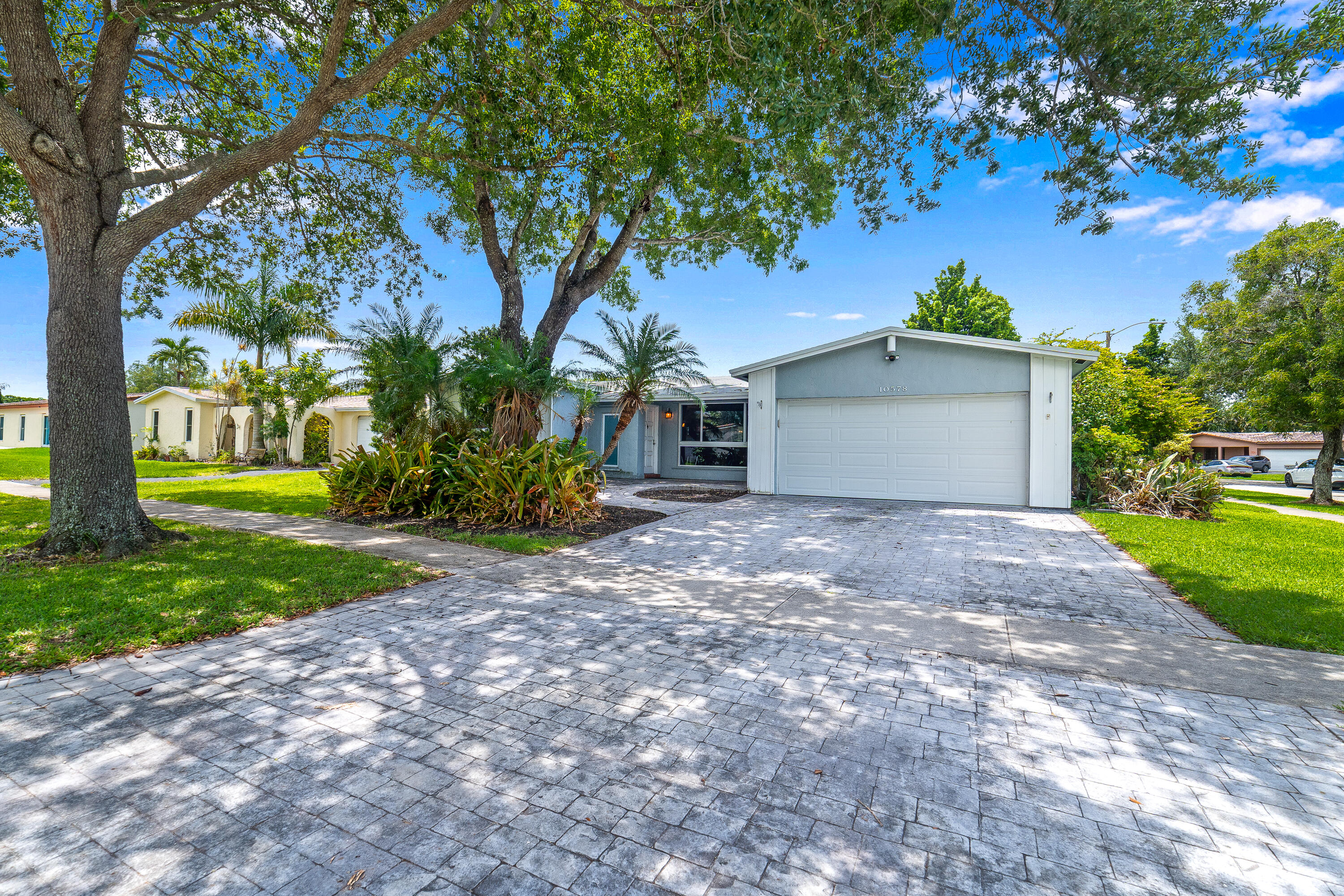 Exceptional opportunity to own a well-maintained home with no HOA restrictions, offering comfort, efficiency, and outstanding outdoor living. Ideally located near schools, shopping, dining, and everyday conveniences, with easy access to I-595, I-95, I-75, and Florida's Turnpike. This residence features three spacious bedrooms and two updated full bathrooms, including a primary bath with a separate tub and shower. Interior finishes include tile and carpet flooring throughout. The spacious kitchen is equipped with stainless steel appliances and is enhanced by a dramatic wall of windows that fills the space with natural light while creating an inviting connection to the outdoor entertaining areas.  Significant improvements provide peace of mind, including impact-rated windows and doors, a re-roof completed in 2012, aluminum storm panels, a burglar alarm system, a 2017 A/C system, a 2013 garage door, a 4' x 6' gate installed in 2018, and a 6-foot shadowbox privacy fence. The garage is equipped with an EV charging station, adding modern convenience for electric vehicle owners. Energy efficiency is a standout feature with a fully owned 10.2 kW solar roof system installed in 2014, resulting in remarkably low electric costs averaging approximately $48 per month year-round. The Florida room roof was professionally sealed in January 2025. Designed for entertaining, the fully fenced backyard offers ample room for a future pool and features a hot tub, screened patio, and outdoor serving counter. The wall of windows opening to the kitchen creates a seamless indoor-outdoor flow, making gatherings and everyday living effortless. The attractive paver driveway leads to the front entrance and is complemented by a beautifully inlaid garden area near the front porch, enhancing the home's curb appeal. Combining thoughtful updates, exceptional energy savings, modern amenities, and versatile outdoor living spaces, this property is ready to enjoy from day one.