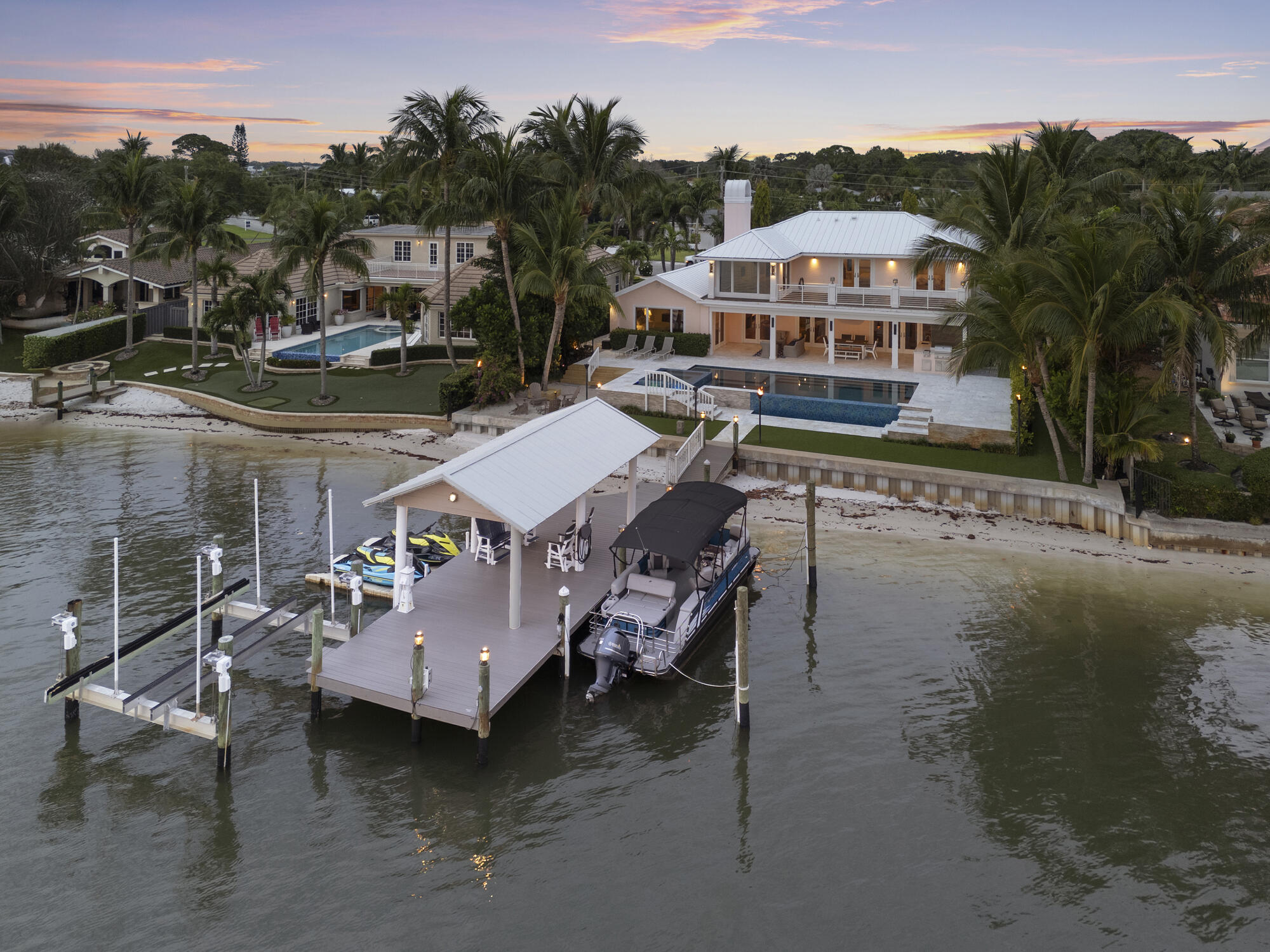 Stunning and rarely available waterfront home in Tequesta, Florida.

This meticulously maintained four-bedroom, five-and-a-half-bathroom home offers luxurious living at its finest, nestled in highly sought-after Tequesta Country Club. Boasting 90 feet of direct water frontage, this property loaded with features is a true entertainer's dream.

Step inside and immediately be greeted by abundant natural light with mesmerizing water views. The kitchen is a chef's dream with both gas and induction ranges, a salamander broiler, multiple ovens, built in espresso machine and more - perfect for preparing meals while enjoying the serene water backdrop. The first floor also includes large walk in pantry, laundry room, family room, living room, primary suite, and two additional bathrooms- one conveniently accessible as a cabana bath. The large primary suite boasts three closets, including a very large walk in closet. In the primary bathroom you will find dual sinks, two water closets, a free standing tub, and a huge steam shower with smart features.

Upstairs are the remaining three bedrooms all with ensuite bathrooms, a large bonus room and an office. Two of the bedroom suites offer french door access to an enormous second floor terrace over looking the stunning Loxahatchee River.

Outdoor living is equally impressive with a large tumbled marble patio, infinity-edge pool and spa, gas beach fire pit and covered newly refinished dock that seamlessly blends into the horizon. Truly a rare find, this covered dock offers an additional shaded outdoor hangout spot to watch the fun on the water and spectacular sunsets. The dock also includes two floating docks for wave runners and a boat lift that can hold up to 24,000 pounds. A small set of stairs leads off the dock to the beautiful private beach area perfect for launching paddle boards, kayaks or just having fun. 

Behind the oversized two car garage is a large outdoor storage shed perfect for storing kayaks and paddle boards, whole house generator and side yard. 

Do not miss out on seeing this one-of-a-kind waterfront property in  the highly sought-after community of Tequesta, Florida.