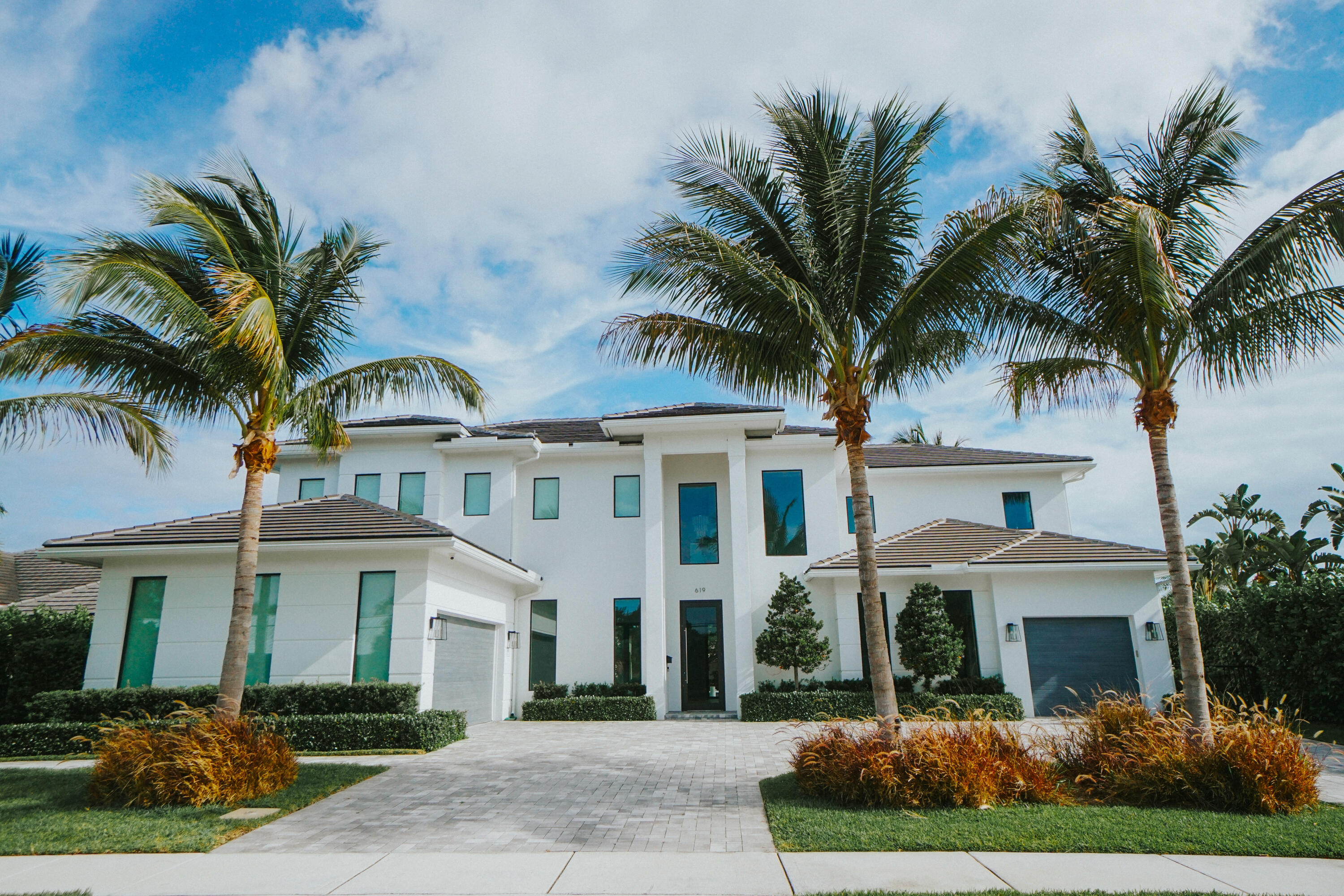 2022 Palm Beach waterfront residence, where timeless design meets modern luxury. Crafted to blend indoor and outdoor living, this home features soaring ceilings, expansive impact windows and doors, and stunning white oak hardwood flooring complemented by custom-built cabinetry throughout—creating a bright, open, and sophisticated atmosphere. The chef's kitchen is a true centerpiece, complete with dual islands, marble countertops, premium Wolf appliances, a Sub-Zero refrigerator, and a spacious walk-in butler's pantry. Designed for both comfort and convenience, the home offers upstairs and downstairs laundry rooms, a private guest suite with cabana bath, a dedicated home gym, and a sleek custom glass staircase. With 5 bedrooms and 5.1 bathrooms, the layout is both functional and flexible.  The upstairs primary suite is a private retreat featuring dual vanities, a spa-like bath, an expansive custom walk-in closet with center island, and a separate shoe and accessory closet. Additional highlights include en-suite bathrooms in all secondary bedrooms, premium TOTO fixtures throughout, and a pre-installed elevator shaft for future convenience. Outdoors, enjoy 90 feet of seawall with dock space, perfect for boating enthusiasts. The resort-style backyard is designed for entertaining, featuring a pool with spa and fire pits, a covered patio with electric screens, outdoor kitchen with gas grill, and a covered balcony for elevated views. Additional features include a 3-car garage with acrylic flooring, full-home security system with cameras, electric shades, surround sound, and designer textured wallpaper accents.