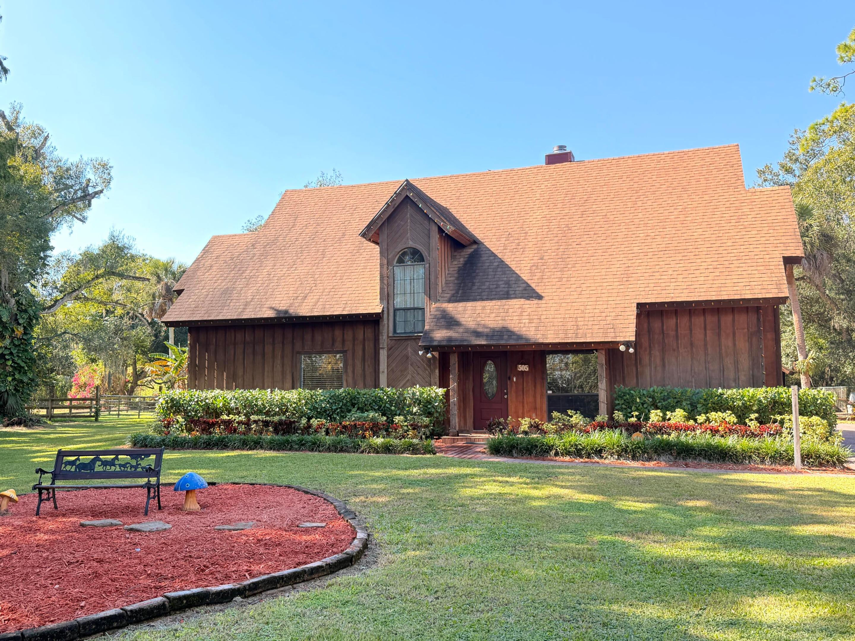 This home will WOW you! On almost 3/4 of an acre, this magnificent home has everything you need. It has a small efficiency beside the home, a carport/workshop area, two separately fenced sections, a horse stable with attached A/C-ed room, outdoor kitchen and private pool and hot tub. It's situated on a dead end road for added privacy and has a newer roof.  The sunken living room features one wall with tall windows to let in the natural sunlight with attached bookshelves on each side and a wood fireplace.  The French doors to the master bedroom lead to a large room and master bath, which includes double sinks, spa tub and separate shower and linen closet.  Upstairs you'll find two bedrooms and a bathroom that has a huge storage area inside. The loft that overlooks the living room has an area to make a quiet retreat. The ceiling beams and kitchen cabinets feature real cedar wood.  Outside the dining room doors, you'll find the outdoor kitchen with covered seating area and a heated saltwater pool and hot tub that's completely screened in. The spacious yard has banana and mango trees, large shade trees, fire pit area.  This home has a newer roof.