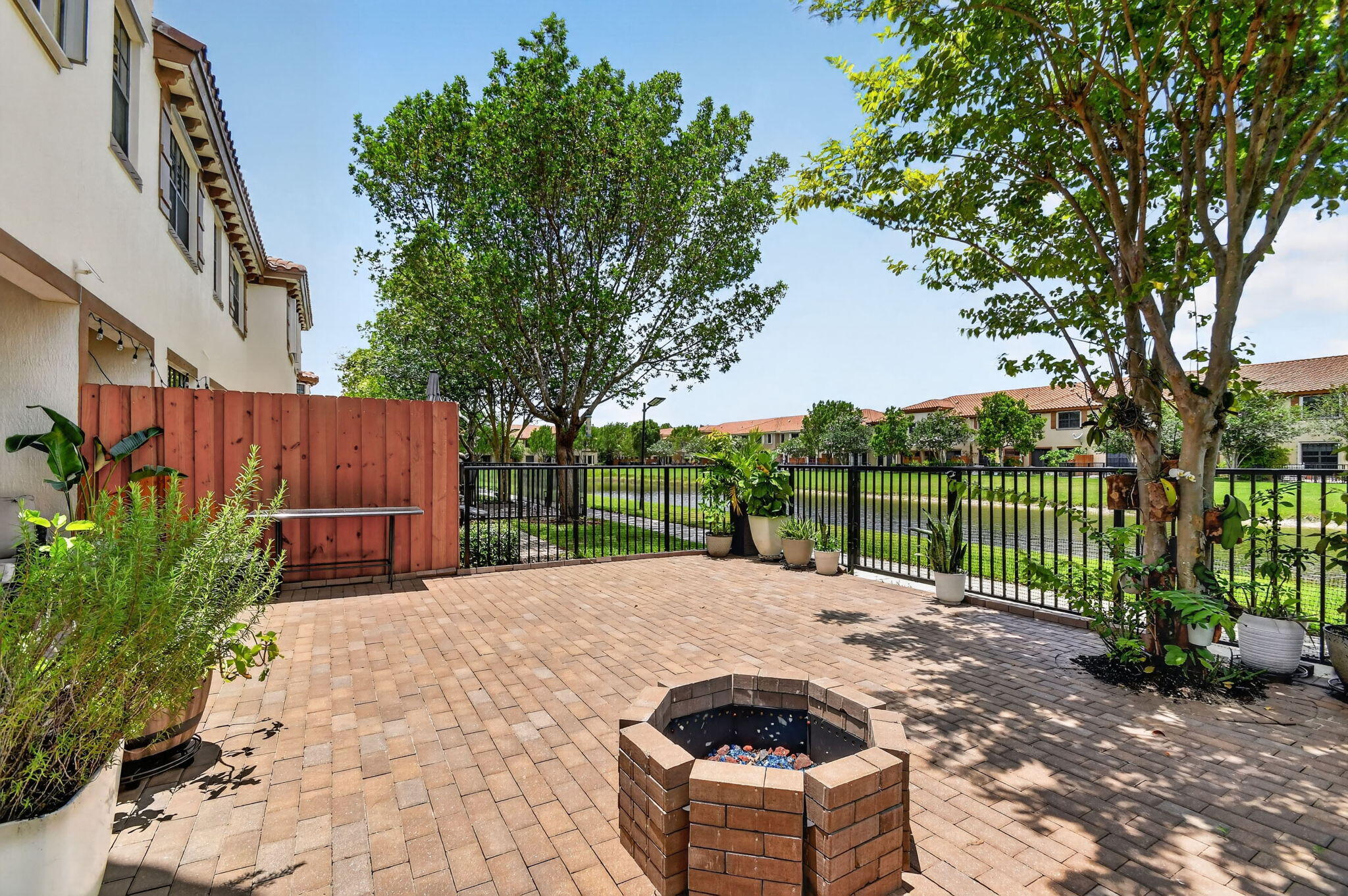 Welcome to your own personal oasis in the boutique community of Wellington Parc. This inviting rarely available end unit  4 bedroom 3 bath 2 car garage luxury unit has a FENCED WATERFRONT PAVER PATIO with a new fire pit.  Owner added a MINI-SPLIT A/C to the epoxy coated garage and is currently using as a family room and gym, with a separate storage area and a whole house water system. The open kitchen has dark wood cabinets. stainless steel appliances, granite, a spacious kitchen island, and a pantry. NO CARPET!(tile downstairs and luxury vinyl stairs and upstairs. Full bath and a laundry room with a sink and extra storage area, dining area, and large great room with tv mount downstairs. Includes high end lighting and a ring camera and system which tenant can activate if desired. Grand ... primary bedroom has a fabulous built-out walk-in closet, open lake view, and ensuite bathroom with dual sinks, separate shower, and large soaking tub. Guest bath includes dual sinks and a combo tub/shower. The two guest bedrooms come with wall mounted tv's. Accordion shutters throughout for hurricane protection. The community has a gate and a pool. Great schools ! Close to Mall, Restaurants, Medical, Polo, Whole Foods, Trader Joe's, Starbucks.