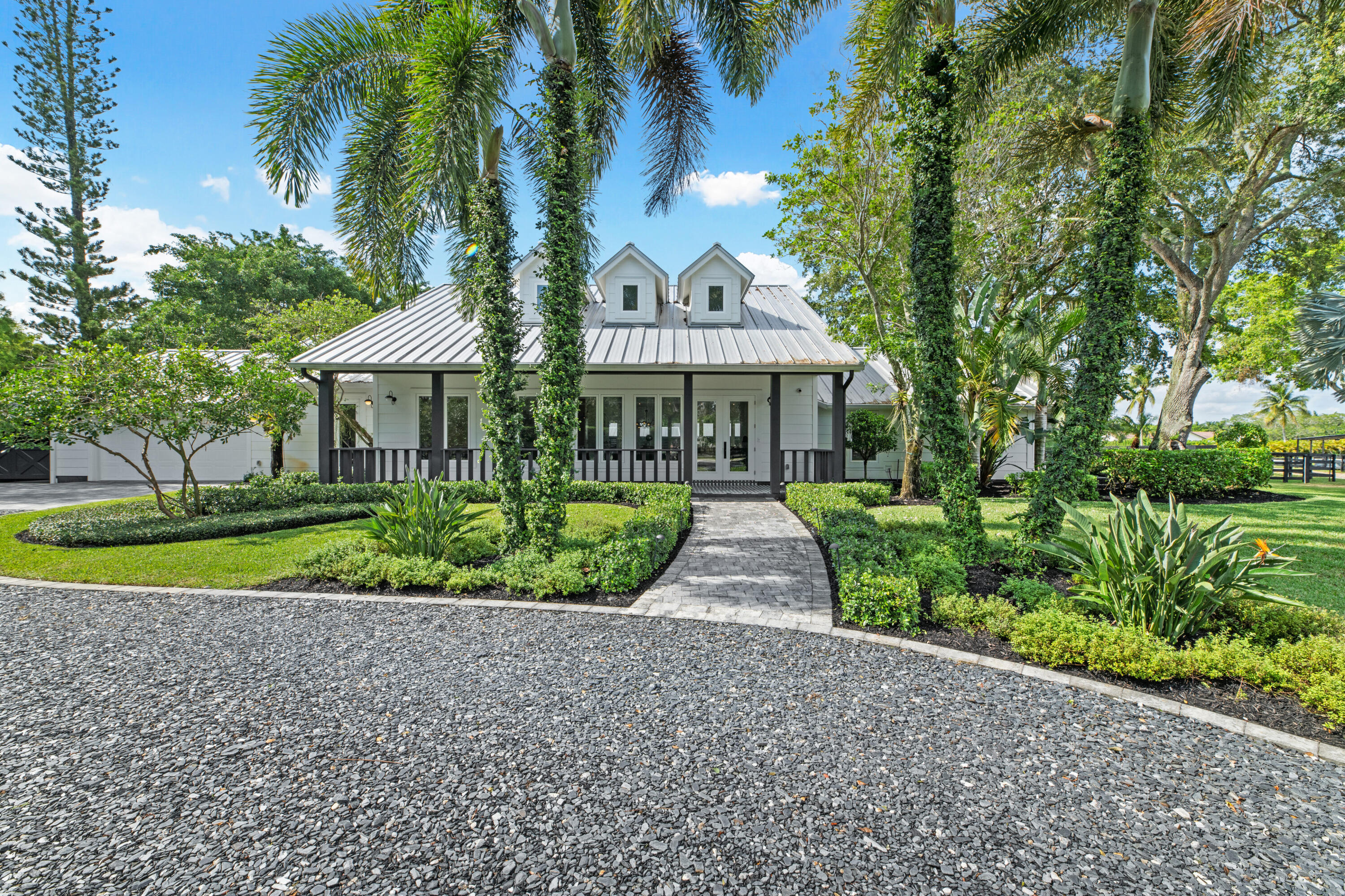 Welcome to your dream equestrian oasis in the heart of Saddle Trail! Spanning an impressive 4.75 acres and offering unparalleled convenience with a short hack to the renowned Wellington International (WEF). Immerse yourself in the equestrian lifestyle with this meticulously renovated 4-bedroom, 4.5-bath home, with an office/den and breathtaking views of the property. As you step inside, you'll be captivated by the light and open floor plan. The home was fully renovated in 2020 and designed for both comfort and entertainment. Featuring a split floor plan, there are a total of four bedrooms, each with its own en-suite bathroom. The master suite wing is a true retreat, featuring his and hers water closets and walk-in closets, an oversized dual shower, luxurious soaking tub, and a private laundry area. All windows and doors have been upgraded to impact glass, and the mud room was upgraded with a dog wash station. The heart of the home lies in the custom chef's kitchen, complete with Thermador appliances and ample counter space. Flowing seamlessly into the dining and entertaining areas, this space is perfect for hosting gatherings or enjoying intimate meals. Discover the hidden butler's pantry/bar, adding an extra touch of luxury and convenience. No detail has been overlooked in this home, which is equipped with RTI-controlled systems, including a 16-color video security system. You'll find two barns with plentiful airflow on the property, totaling 14 stalls, providing ample space for your beloved horses. Storage areas ensure that all your equipment is neatly organized, while the air-conditioned tack room features a laundry and half bath for added convenience. Equestrians will appreciate the new expansive all weather ESI arena with  textile footing, measuring approximately 160 x 230. Additional amenities include a covered viewing area with speakers and power, a covered MK 6 horse walker, and plenty of space for trailer parking. Separate buildings dedicated to storage add to the functionality and efficiency of this exceptional property. There's ample space available to build more stalls or an additional barn. Don't miss out on this truly one-of-a-kind property. Immerse yourself in the equestrian lifestyle, surrounded by top-notch facilities and unparalleled convenience. Schedule your private viewing today and experience the pinnacle of equestrian living.