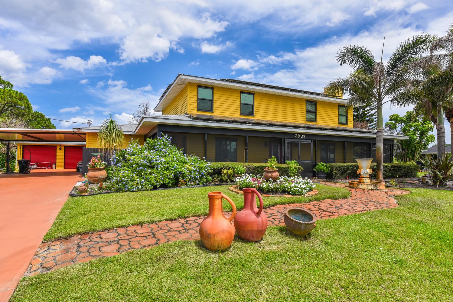 Welcome To The Highly Desirable Sandpiper Bay Community! NO HOA! PARK YOUR BOAT, RV & TRAILER!  With Over 3,000 Square Feet Under Air This 2 Story Home With Wraparound Porch Features 4 Large Bedrooms w/Walk-in Closets, 3 Full Baths, Fomal Livingroom w/Wood Burning Fireplace, Large Family Room w/100" Wall Mounted TV, Enjoy Year-round Outdoor Living With Screened-in Pool, Built-in Grill & Tropical Tiki Bar Perfect For Entertaining Family & Friends, Detached Two Car Garage, 2022 COMPLETE IMPACT GLASS, Two 2024 A/C Units, Two 2023 Tankless Hot Water Heaters, Sprinklers on Well, Pulic Water/Public Sewer. Great Opportunity For Multigenerational Living! Sandpiper Bay Is Home To The Port District On The North Fork of The Saint Lucie River W/River Walk, Canoe/Kayak Launch.