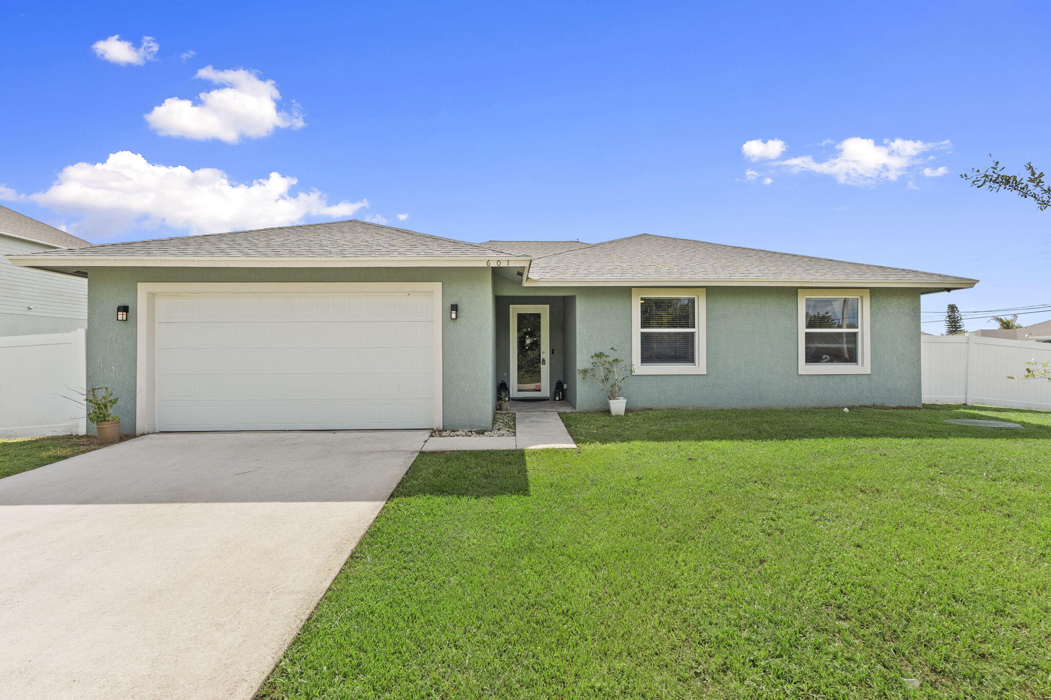 Welcome to this beautifully maintained 3-bedroom, 2-bathroom home built in 2022, offering over 2,100 square feet of living space. Situated on a spacious 0.33-acre corner lot with no HOA, the property features a fully fenced backyard with a white vinyl privacy fence, double entry gate, covered patio, and plenty of room to add a pool. Inside, you'll find an open-concept layout with a desirable split-bedroom floor plan that makes sense. Tile flooring extends throughout the entire home, creating a clean, cohesive aesthetic that's easy to maintain. The kitchen features quartz countertops, soft-close cabinetry, stainless steel appliances, a large walk-in pantry, farmhouse sink and an adjacent dining area. The spacious primary suite offers dual walk-in closets, a double vanity, private water closet, and a frameless glass walk-in shower with dual shower heads. Sliding glass doors provide direct access to the backyard, filling the space with natural light while creating a seamless indoor-outdoor connection. The expansive backyard has endless possibilities for outdoor living, whether you're looking to create a custom pool, store recreational vehicles, or simply enjoy the extra space and privacy. Ideally located in the heart of Port Saint Lucie, you'll enjoy convenient access to shopping, dining, medical facilities, and major transportation routes including I-95 and the Florida Turnpike. Both Newfield and Tradition are just minutes away, offering an abundance of restaurants, shopping, entertainment, community events, and everyday conveniences. The beautiful Treasure Coast beaches are only 25 minutes away, while West Palm Beach, Palm Beach International Airport, Vero Beach Regional Airport are approximately 45 minutes from your doorstep, making commuting and travel a breeze.
