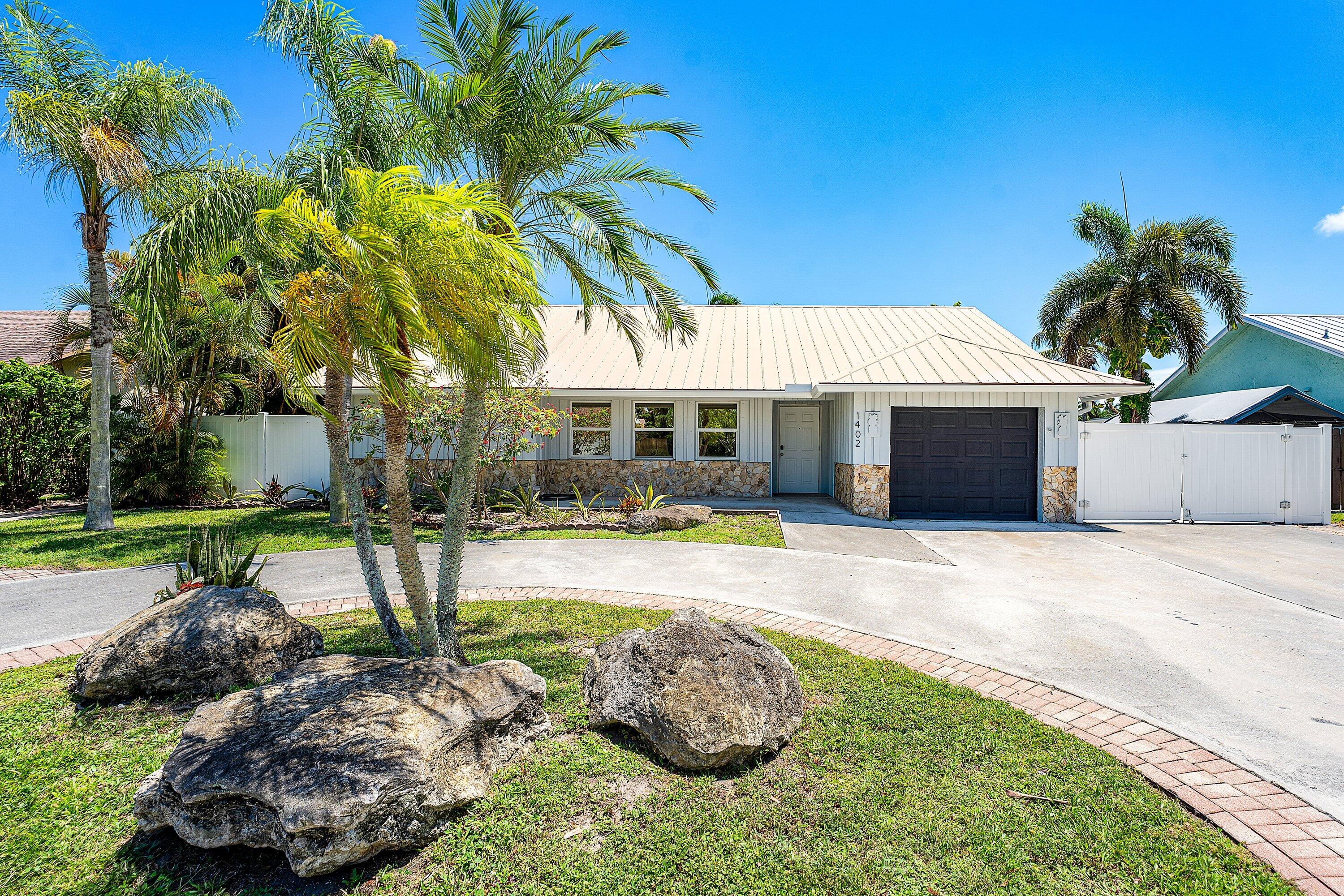 Tropical waterfront living awaits in this beautiful Delray Beach gem, tucked within a quiet, artfully landscaped neighborhood just moments from Atlantic Avenue. Set beneath a newer aluminum roof, this spacious home offers an open-concept floor plan with more than 1,900 square feet of living space and consistent ceramic tile flooring throughout for a clean, cohesive feel. The brand-new dock is ready for your boating lifestyle, with space to enjoy boats, kayaks, jet skis, paddleboards, and days spent on the water. Inside, the home features generously sized living areas, a large laundry room, fitted closets for organized storage, and two waterfront bedrooms that bring the serene setting right into your everyday routine. The backyard is the true showpiece — a private tropical retreat surrounded by palm trees, zen-inspired landscaping, and a sparkling pool maintained by the owner. Enjoy grilling, gardening, relaxing by the water, or hanging a hammock beneath the trees. A year-round producing avocado tree adds the perfect South Florida touch. With a circular driveway, 1-car garage, and plenty of parking, this property blends comfort, convenience, and laid-back coastal living in one of Delray Beach's most desirable locations. Tropical paradise, waterfront access, and Atlantic Avenue just minutes away — this is the lifestyle you've been waiting for.
