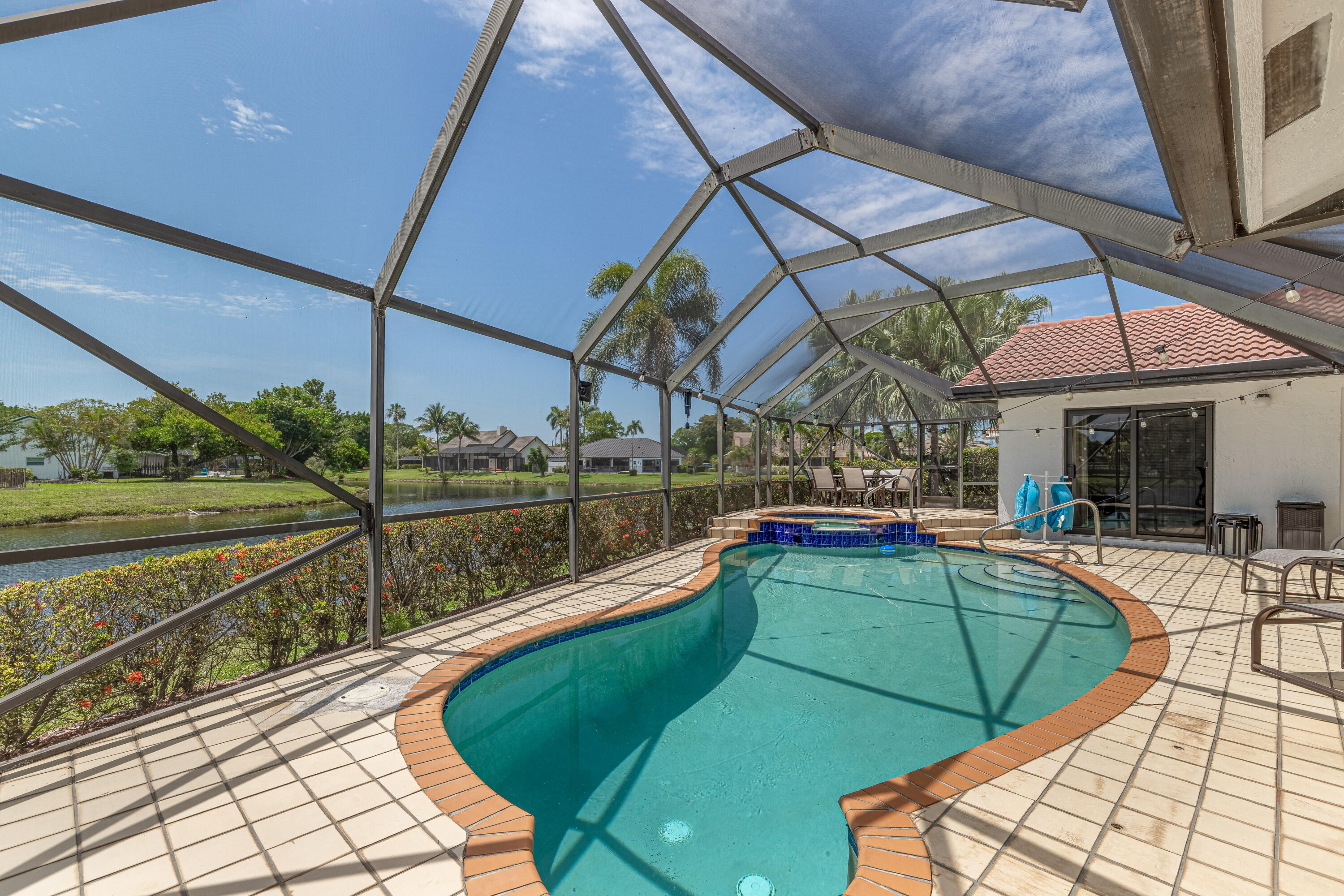 PRICE IMPROVEMENT! 4 BEDROOM + DEN HEATED POOL HOME ON A CUL-DE-SAC featuring impact windows & doors, 2 newer A/C systems and spectacular wide lake views. Located in desirable Palm Ridge at Woodmont, this spacious waterfront residence offers over 2,400 sq ft under air with an open floor plan, soaring ceilings and abundant natural light. Major updates completed within the last 5 years include two A/C systems, pool heater and all appliances. Enjoy breathtaking lake views from multiple living areas, including the kitchen, and wake up to tranquil water views from the primary suite. The screened heated pool and patio create the perfect setting for entertaining family and friends while enjoying South Florida living year-round. Flexible den space is ideal for a home office, guest room, playroom or hobby area. Situated on a quiet cul-de-sac and conveniently located near golf, parks, shopping, dining and major highways. Rare opportunity to own a waterfront pool home that combines space, updates, impact protection and an exceptional lakefront setting.
