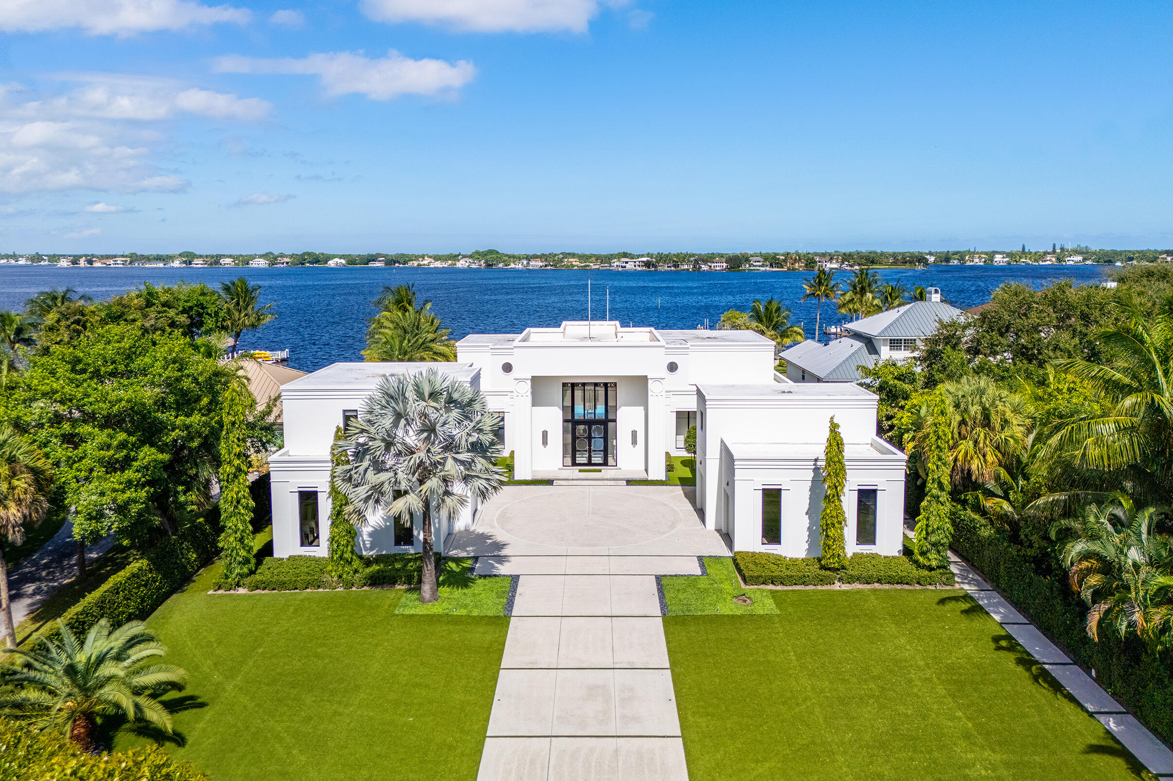 Experience the art of luxury living in this spectacular modern estate on the scenic Loxahatchee River in Jupiter, Florida. Tucked away on a private street, this custom-built masterpiece blends architectural sophistication, advanced technology, and the serene beauty of South Florida waterfront living.  Beyond the stately gates, the resort-style setting offers 127' of waterfrontage, a covered outdoor kitchen with large island and seating area and a 20' x 40' pool with spa. The meticulously landscaped grounds feature artificial turf lawns ensuring a pristine look year-round.  The private dock, with boat lift and floating dock for smaller boats, provides direct boating access to the Intracoastal Waterway and the Atlantic Oceanâ€''perfect for those who treasure the coastal lifestyle. The heart of the home is a grand great room, designed for both comfort and sophistication, with soaring ceilings and panoramic river views. The chef's kitchen is a true showpiece featuring a large central island and Miele appliances.  Custom terrazzo flooring, solid wood doors, and bespoke wood cabinetry and moldings throughout the home showcase craftsmanship of the highest caliber.  This residence offers six bedrooms, six full baths and four half baths.  The bedrooms include a primary suite with a spa-like bathroom, four en suite guest bedrooms for luxurious privacy and a guest suite featuring its own sitting room and kitchenette providing additional flexibility for guests or staff. Laundry rooms on each level add convenience for large-scale living.   Designed for the ultimate entertainer, the home's amenities include formal and casual dining areas, a 1,500-bottle temperature-controlled wine cellar and wet bar, all overlooking the tranquil riverfront.  Every element of this home reflects thoughtful design and superior engineering. The Crestron home automation system provides effortless control of lighting, climate, and security, complemented by a Sonos sound system with 24 invisible speakers. Comfort and efficiency are ensured by four tankless water heaters, six zoned air-conditioning units, and a comprehensive camera and security system. The air-conditioned garages feature poured concrete flooring and a dedicated second-level storage area, offering both functionality and durability. Built with a concrete and steel structural system, the design pressures of this home can withstand winds exceeding 200 MPH, this residence is truly built to last.  This exceptional Jupiter estate embodies the pinnacle of South Florida living-a boater's and golfer's paradise where privacy, elegance, and waterfront tranquility converge.  Private. Polished. Perfectly Jupiter.
