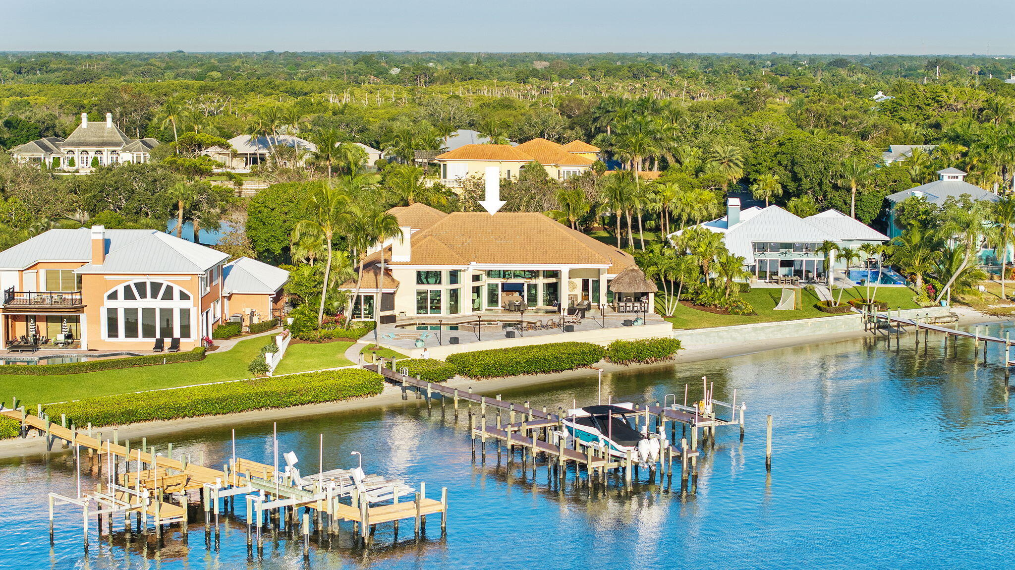 Waterfront Luxury Estate within Bay Pointe's exclusive gated enclave. This home boasts 135' of frontage on the St Lucie River, catering to boating enthusiasts with 2 lifts accommodating vessels up to 30,000 & 9,000 lbs. Impeccably remodeled by Straticon & adorned with Pineapple House interiors, every detail radiates sophistication.  Escape to the Master Suite, including his and her closets & a custom marble bathroom. Experience peace of mind with all Impact Windows & Doors, & a whole house generator. Outside, discover a tropical paradise, complete with a fire pit, Tiki Bar, saltwater pool, all framed by lush landscaping. This residence features 5 luxurious ensuite bedrooms, his & her offices, & a versatile bonus room, offering ample space for work & play.