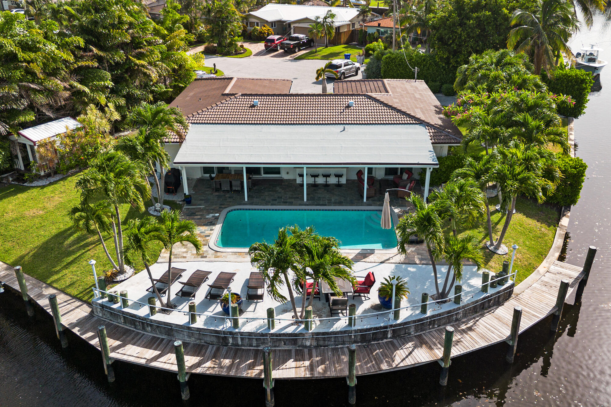 Rare opportunity to own a 4-bedroom, 2-bath waterfront pool home on an oversized point lot with approximately 220 feet of waterfront, panoramic water views, full impact windows and doors, a new roof installed in 2024, and a dock rebuilt in 2019. With only one fixed bridge to the Intracoastal, this exceptional property offers convenient boating access to the waterways and Atlantic Ocean while delivering the ultimate South Florida waterfront lifestyle.  Designed to embrace indoor-outdoor living, the open-concept floor plan seamlessly connects the main living spaces to the expansive outdoor entertaining areas. Rich wood-look porcelain tile flooring flows throughout the home, while a dramatic picture window frames beautiful views of the pool and waterway from the moment you enter.  The updated kitchen is designed for both everyday living and entertaining, featuring rich wood cabinetry, granite countertops, stainless steel appliances, mosaic tile backsplash, and a large peninsula with bar seating. A standout pass-through serving window opens directly to the covered lanai and outdoor bar seating, creating effortless indoor-outdoor entertaining.  The spacious primary suite serves as a private retreat with direct sliding glass door access to the pool patio, a beautifully remodeled ensuite featuring dual vanities, an oversized frameless glass walk-in shower, and a custom walk-in closet.  Step outside to experience what truly sets this property apart. The massive covered lanai spans nearly the entire width of the home, creating a true outdoor living room overlooking the heated swimming pool and spectacular waterfront setting. Multiple lounging and dining areas, an expansive pool deck, mature tropical landscaping, and generous green space on both sides of the property provide exceptional privacy and flexibility rarely found on waterfront homes.  Boating enthusiasts will appreciate approximately 220 feet of dockage wrapping two sides of the property, a boat lift, and ample space for multiple vessels and watercraft. With only one fixed bridge at Federal Highway (approximately 11 to 14 feet of clearance depending on tide), you'll enjoy convenient access to the Intracoastal Waterway and ocean beyond.  Additional highlights include a climate-controlled two-car garage, circular paver driveway, a dedicated side parking pad ideal for a boat trailer or additional vehicles, and abundant guest parking. Pompano Beach is one of South Florida's fastest-growing coastal communities, offering an elevated blend of Waterfront lifestyle, convenience, and long-term investment appeal. The revitalized beachfront offers world-class restaurants and luxury destinations including The W, Ritz-Carlton, and Waldorf Astoria. Enjoy the Pompano Beach lifestyle with an abundance of rooftop lounges, casual oceanfront dining, the iconic fishing pier, and new waterfront parks designed for an active, outdoor lifestyle. Downtown continues to evolve with the completion of the new City Hall and expanded civic spaces, while walkable neighborhoods and the Circuit electric rideshare make getting around easy and efficient. With quick access to intracoastal waterways and ocean access just minutes away, Pompano Beach is a boater's dream community. Local pickleball courts, neighborhood parks, and multiple championship golf courses throughout the area are the cherry on top. For travelers and commuters, you'll have easy access to US-1 and I-95. FLL Int'l Airport is 20 minutes away, Miami Int'l Airport is 45 minutes away, and Palm Beach International Airport is 40 minutes away.